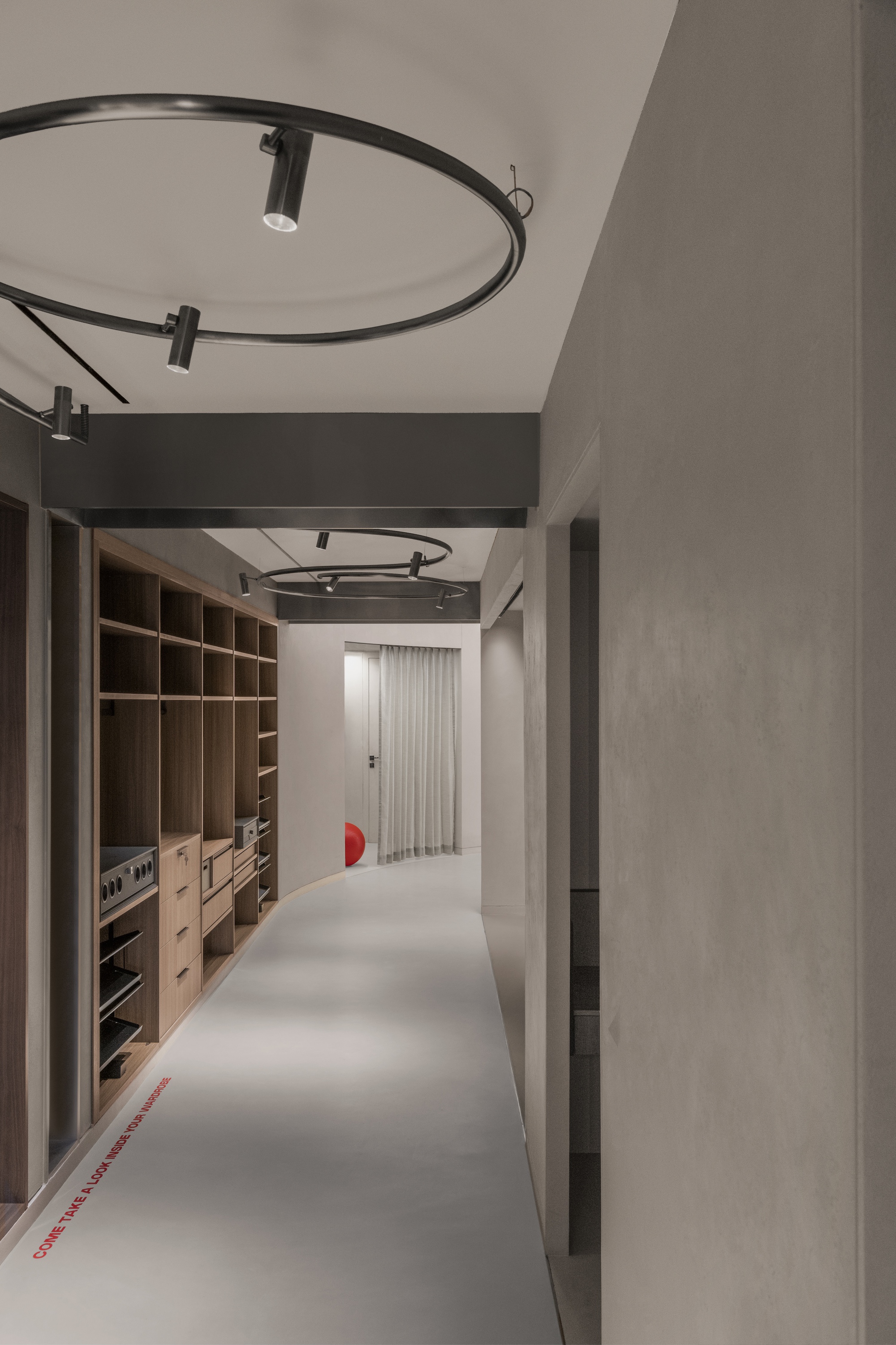 Hallway with timber storage joinery along one side and circular track lighting suspended overhead