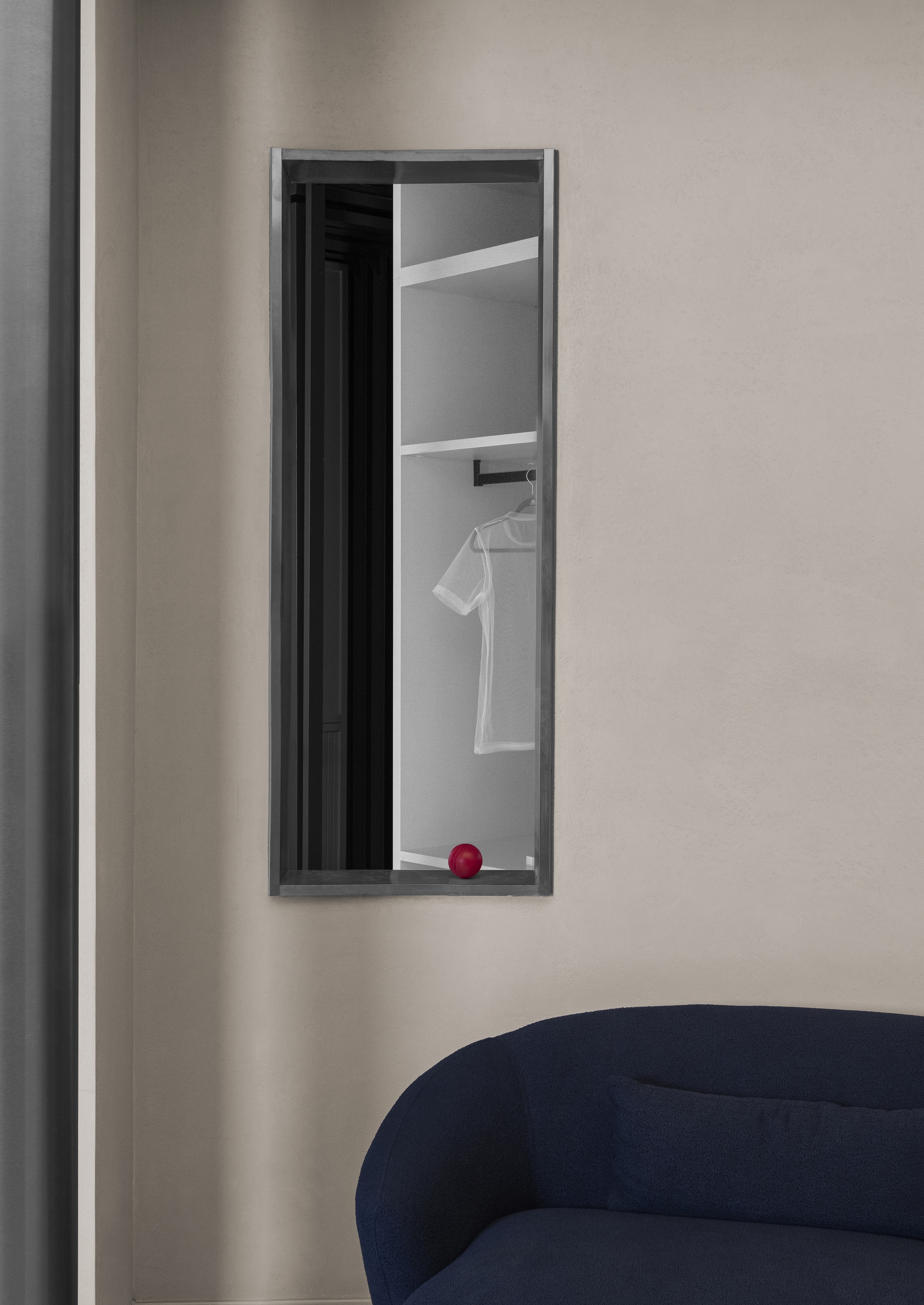 Tall narrow aperture in the wall framing a view into a wardrobe with hanging garment