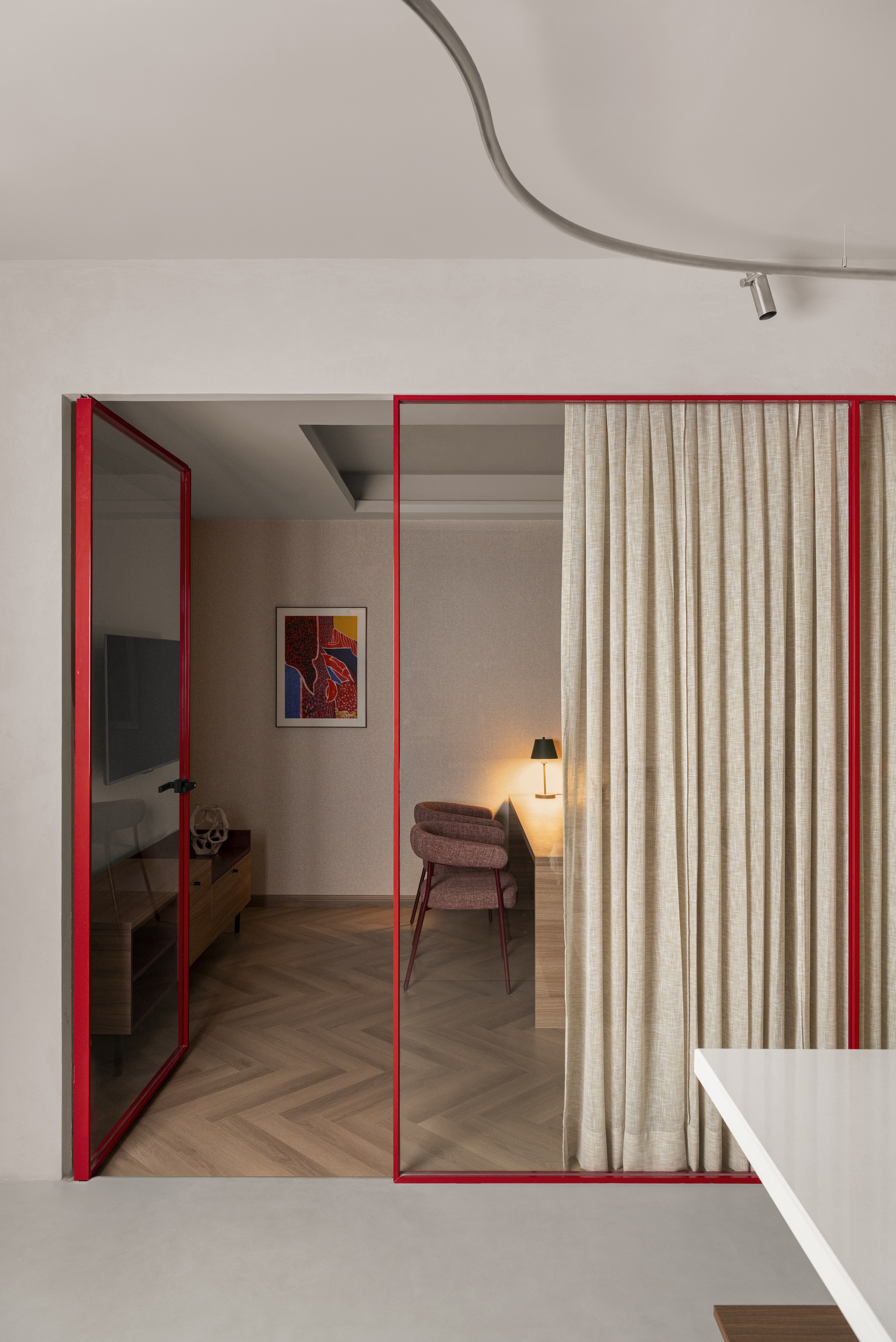 Red steel framed sliding doors with glazing and curtain panels opening to a bedroom beyond