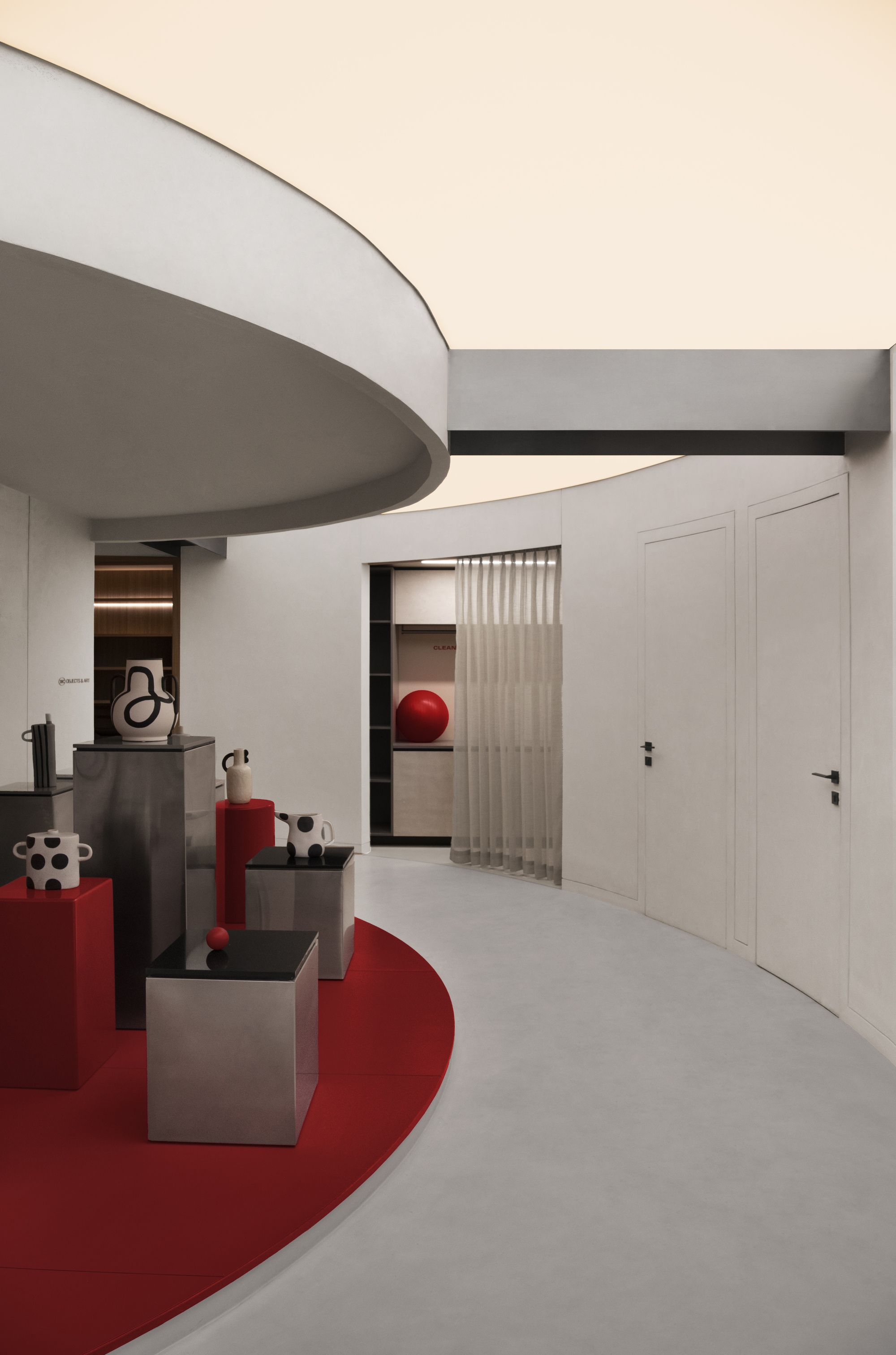 Curved ceiling edge above a red floor graphic with sculptural objects on grey pedestals