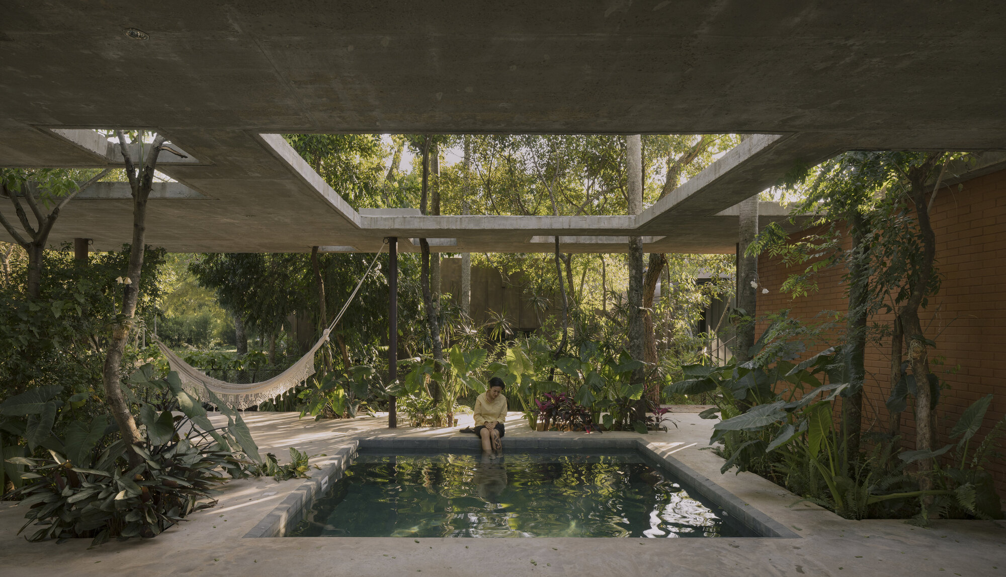 Covered courtyard with concrete roof slab framing a pool surrounded by dense tropical vegetation