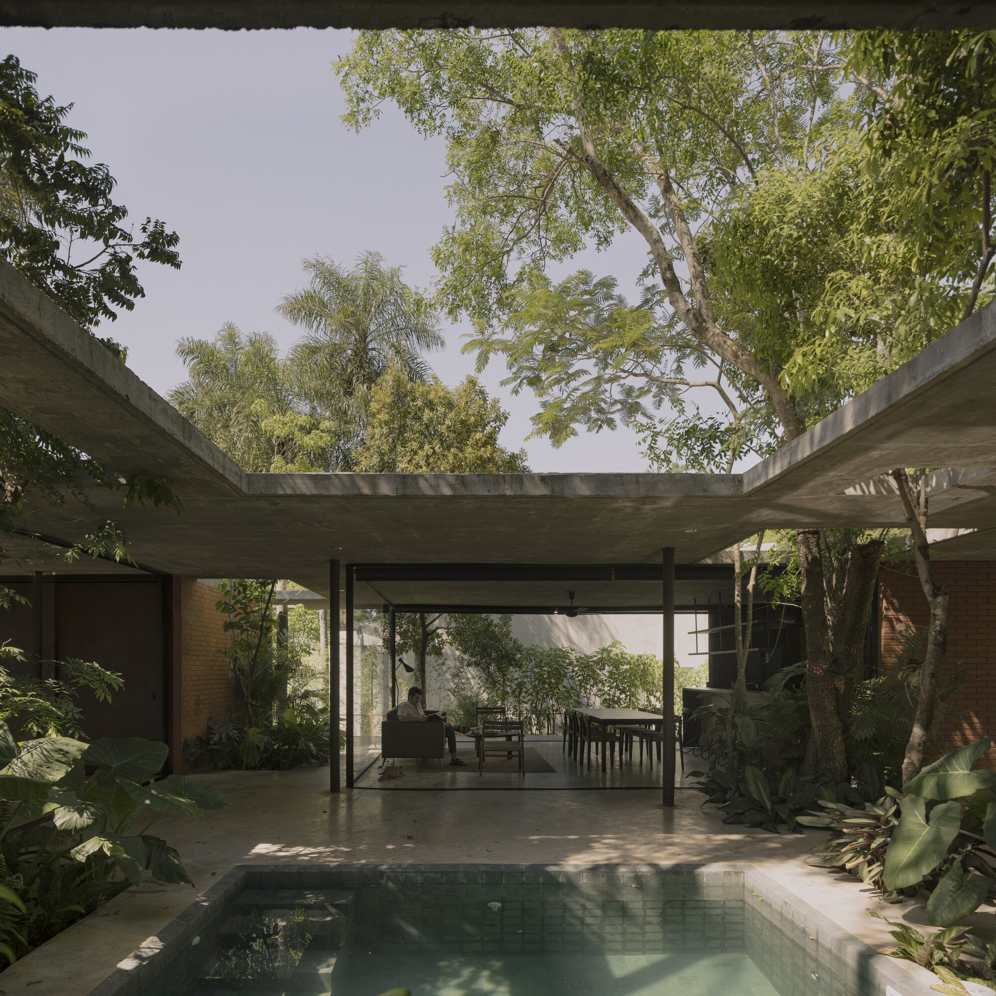 View through the central courtyard showing pool, dining area and open roof framing the canopy above