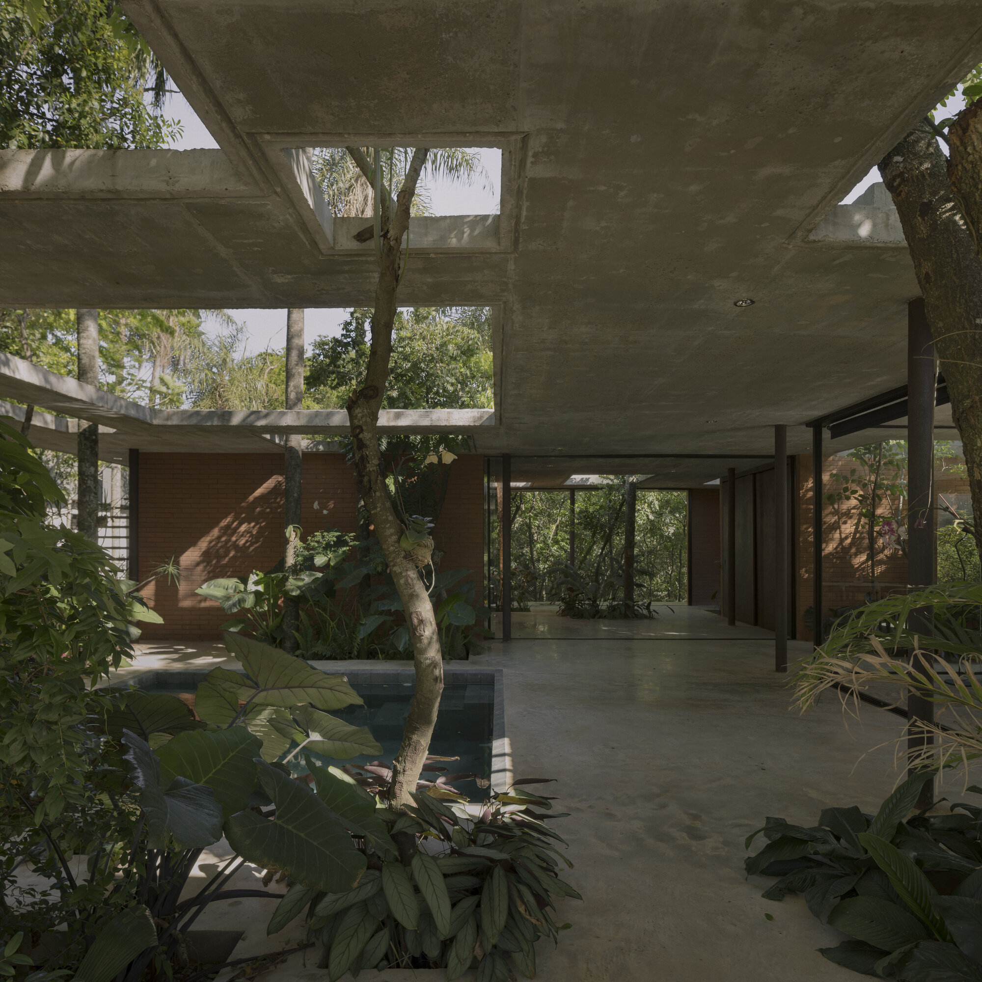 Interior courtyard with reflecting pool surrounded by concrete columns and tropical plantings beneath cantilevered slabs