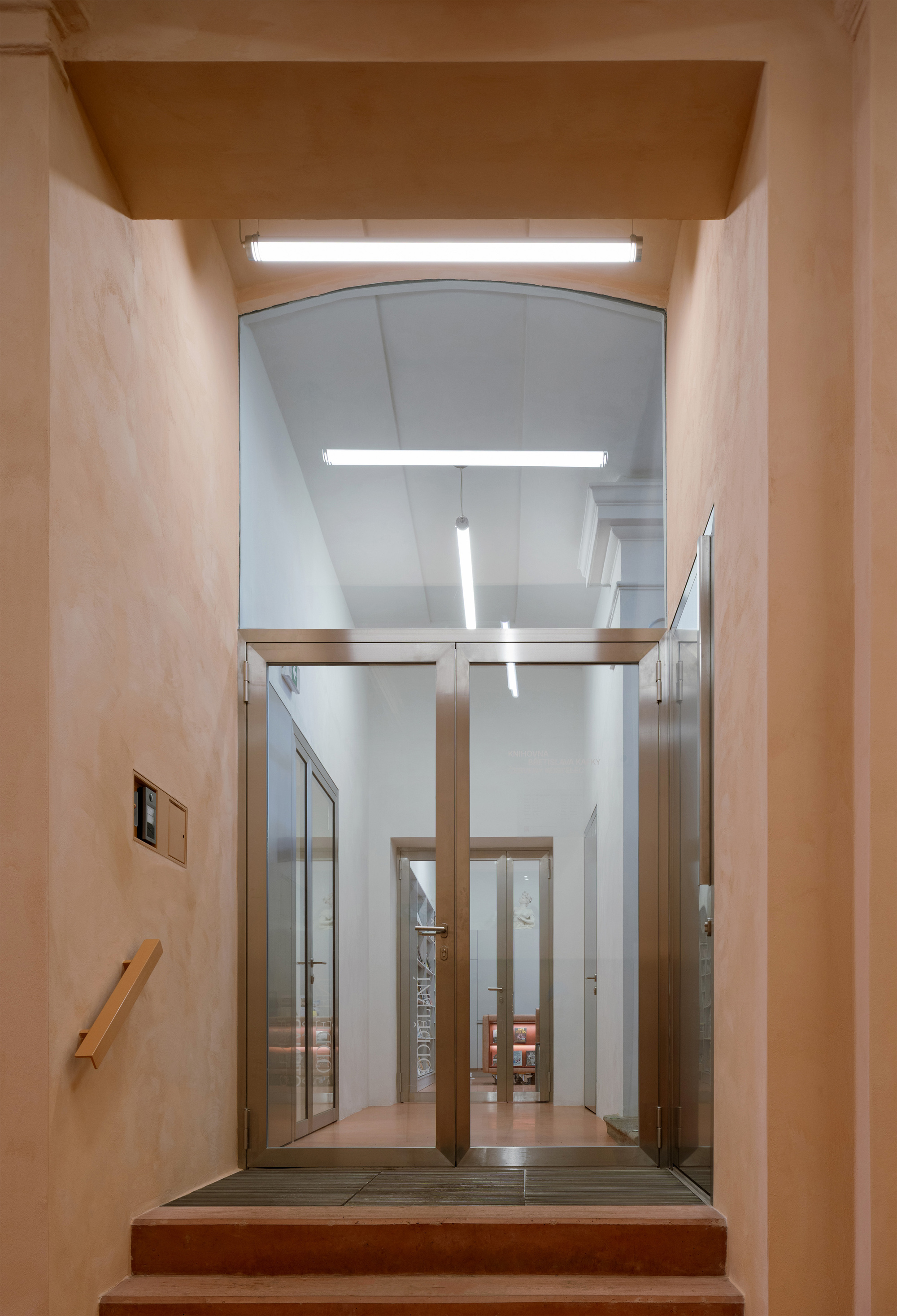 View through arched doorway showing glazed elevator cab beneath a plywood-clad ceiling alcove