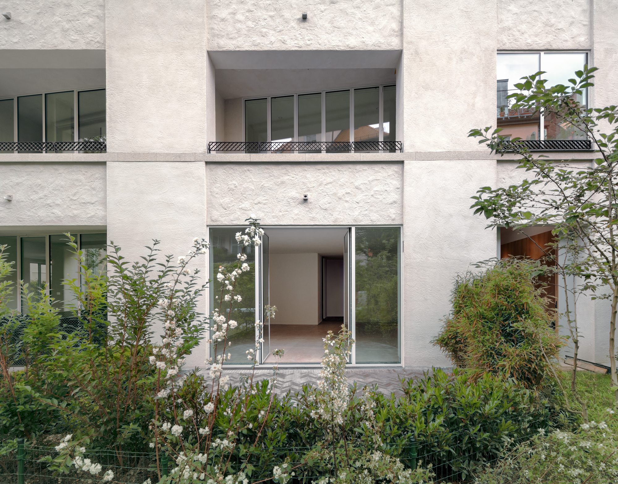 Ground floor terrace with open sliding glass doors leading to the interior and flowering rose bushes