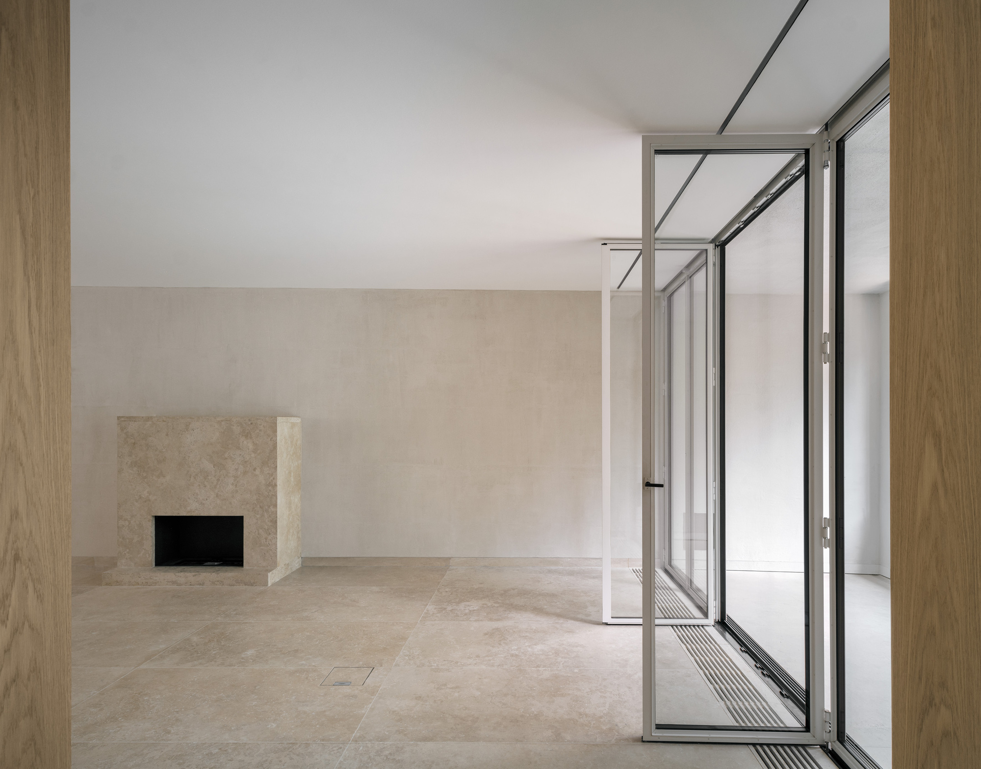 Living room with limestone fireplace surround and open terrace doors framed by oak paneling