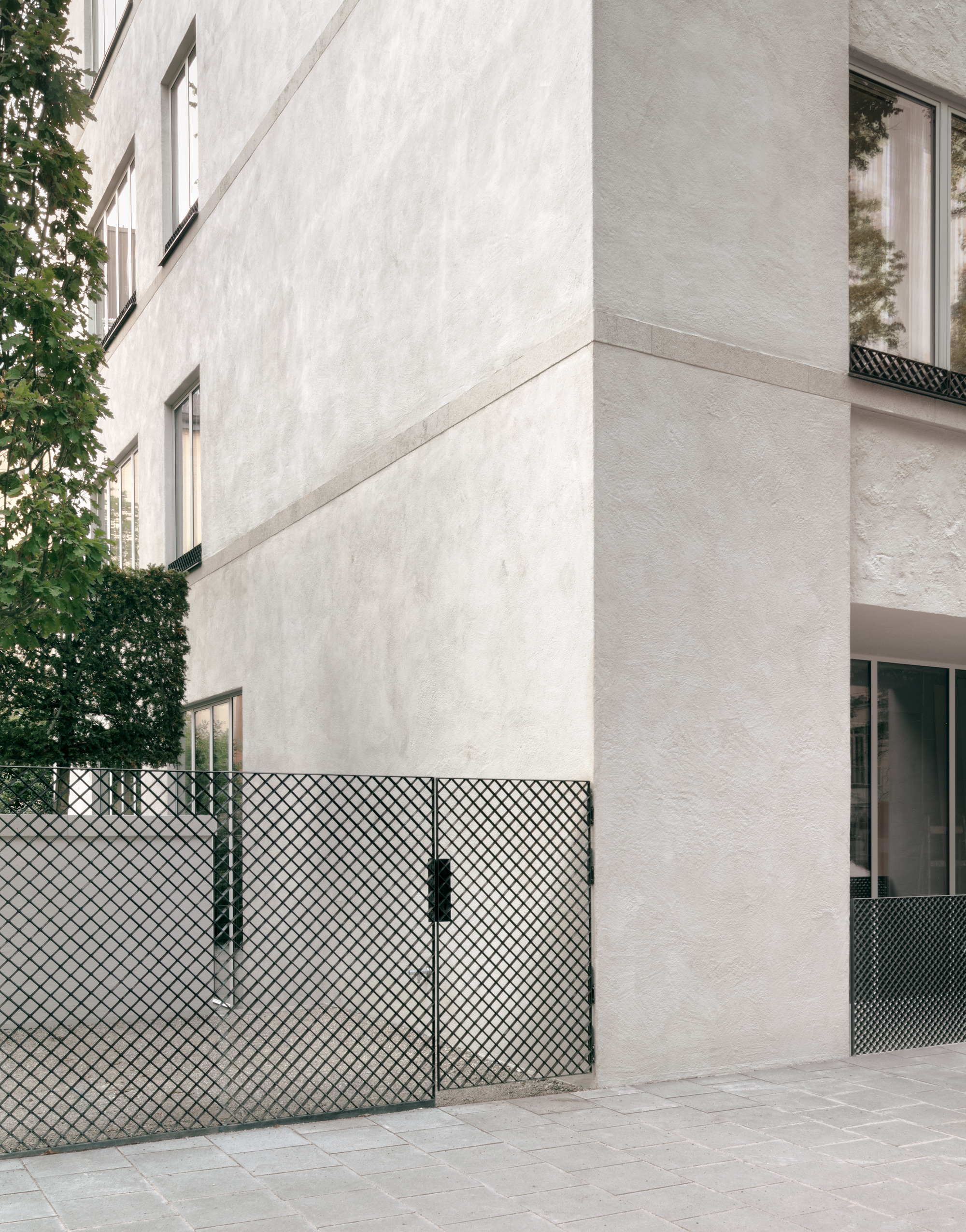 Exterior corner detail showing the white stucco wall meeting the diamond mesh balcony railing