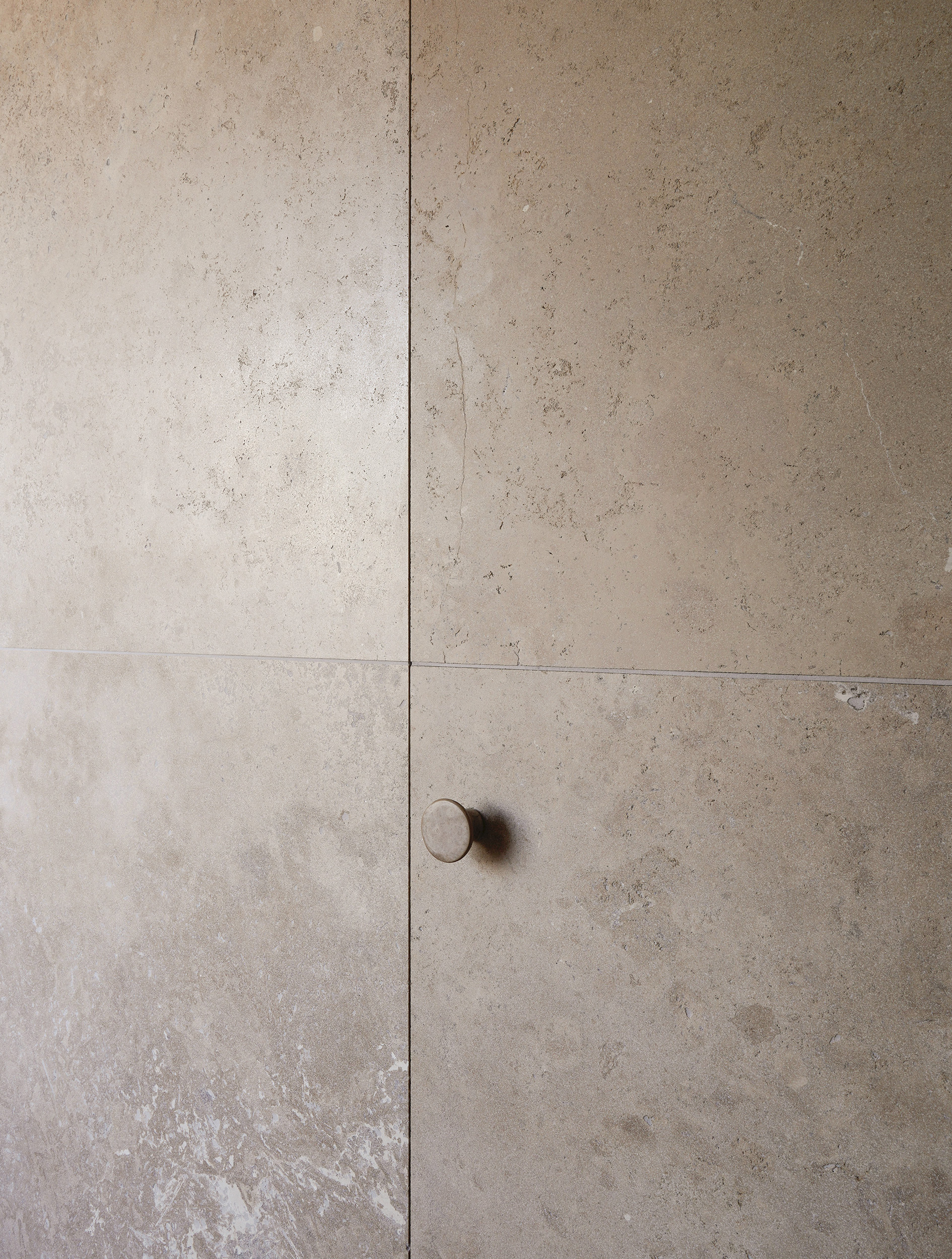 Limestone wall panels with recessed circular door handle at panel joint