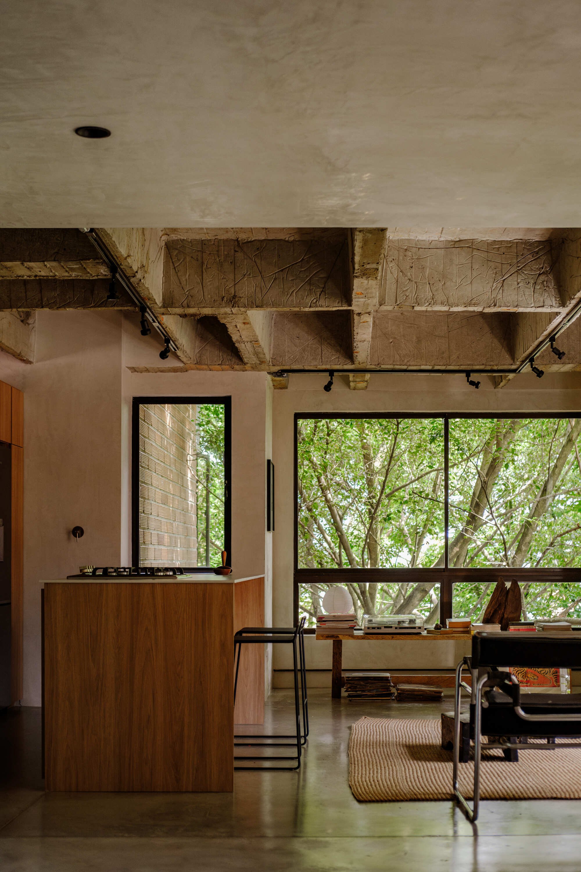 Kitchen with exposed timber ceiling structure, timber island, and windows framing trees outside