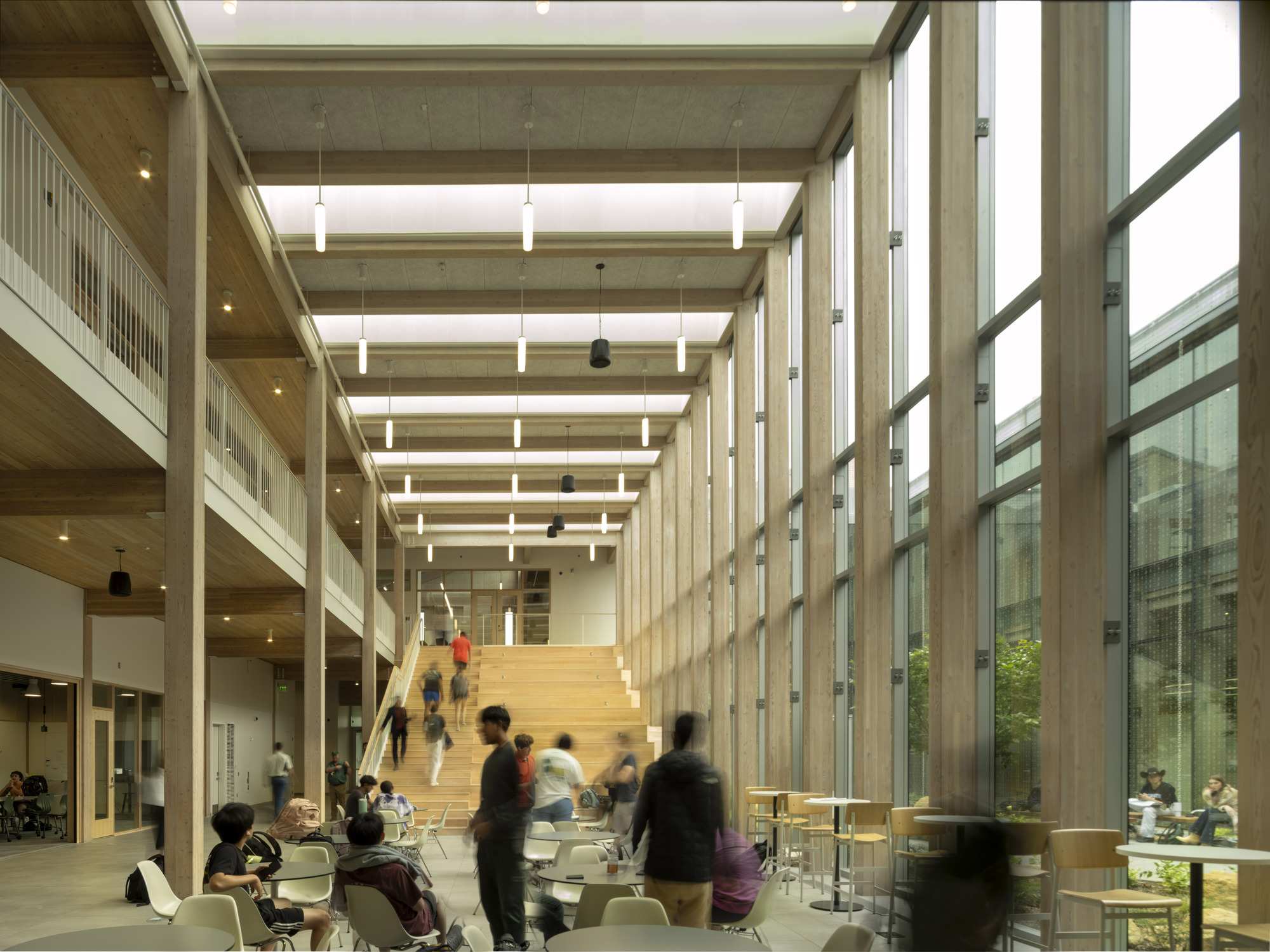 Interior atrium with exposed timber ceiling beams, wide timber staircase and students gathered below