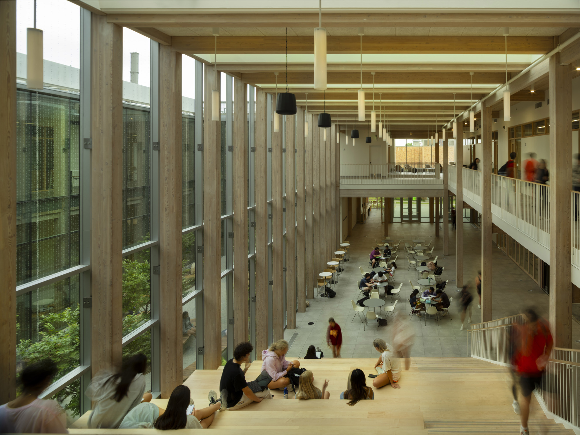 View down into double-height lobby with timber column screens and people seated along balcony edge