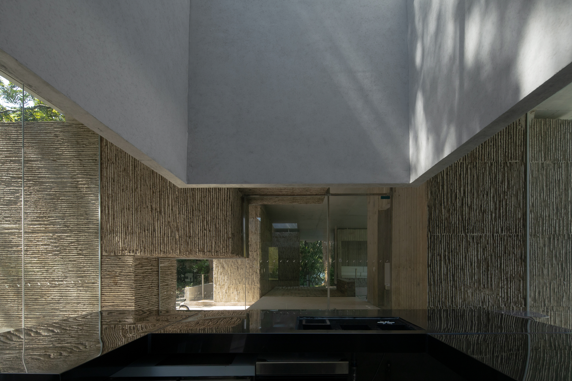 Interior courtyard with reflecting pool flanked by textured stone walls and an open concrete ceiling