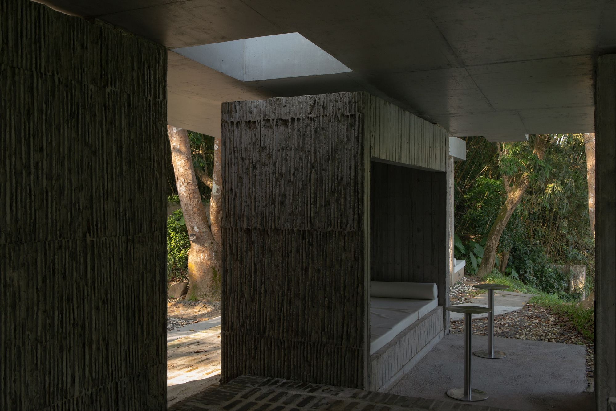 Interior passage with skylights and ribbed concrete walls opening to landscaped courtyards
