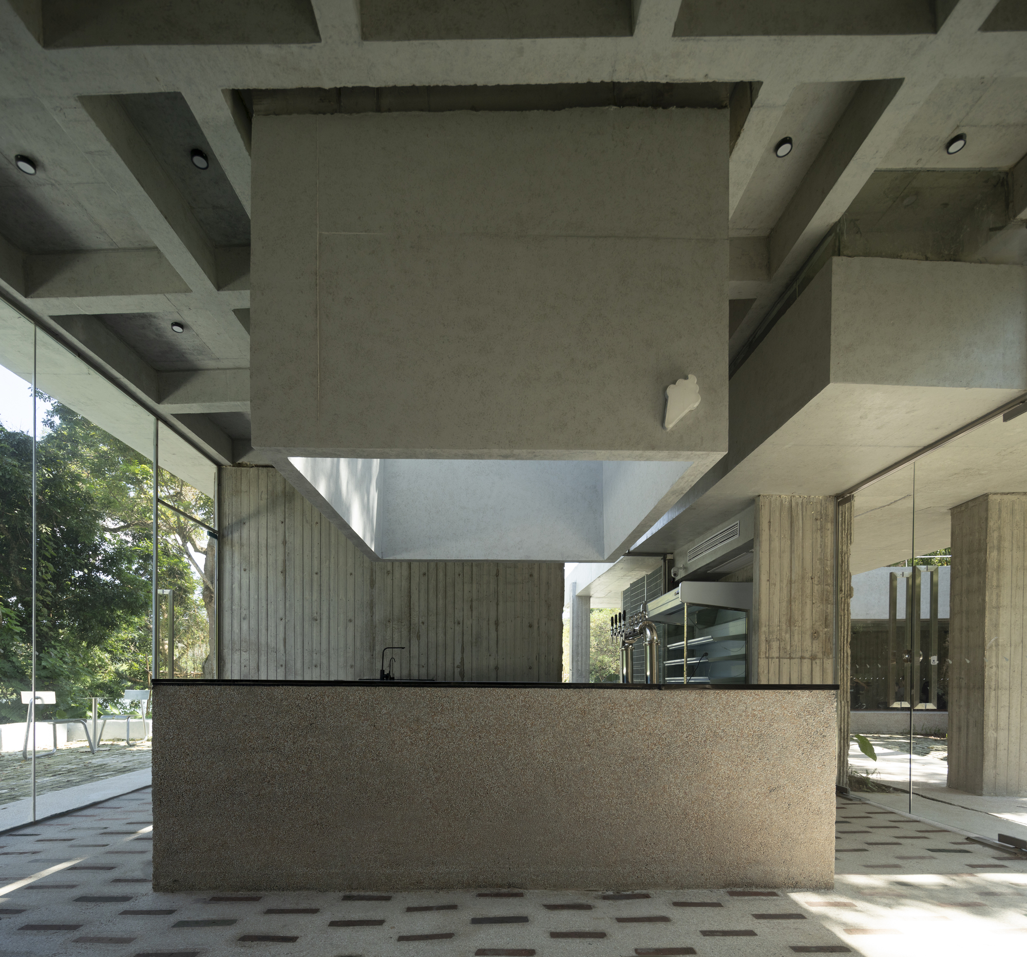 Interior reception counter with terrazzo base and vertical timber cladding beneath a coffered concrete ceiling