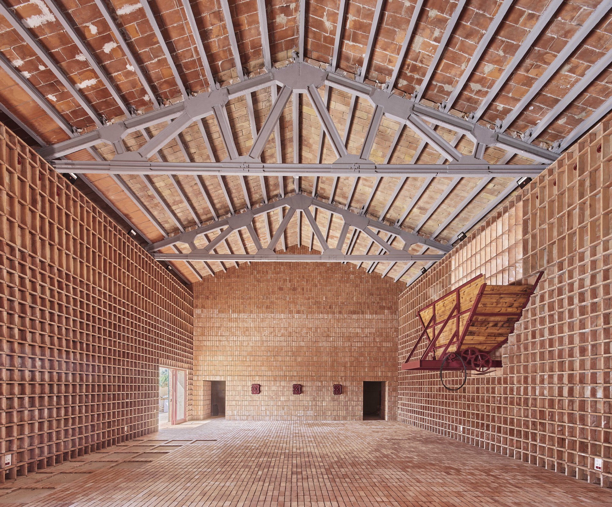 Interior hall with brick walls and vaulted tile ceiling supported by exposed grey steel trusses