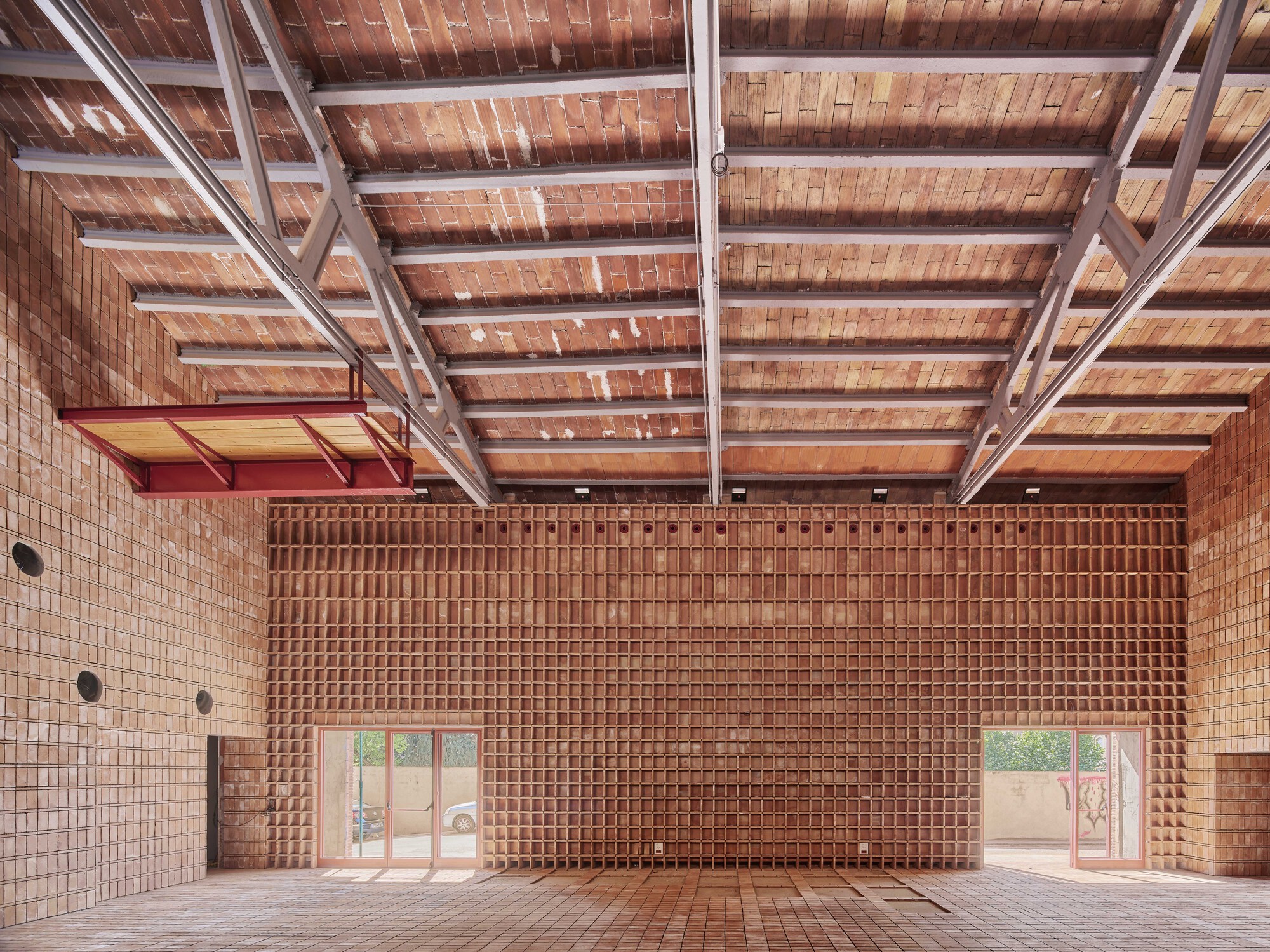 Interior view showing brick walls, exposed steel roof structure, and glazed doors opening to a courtyard