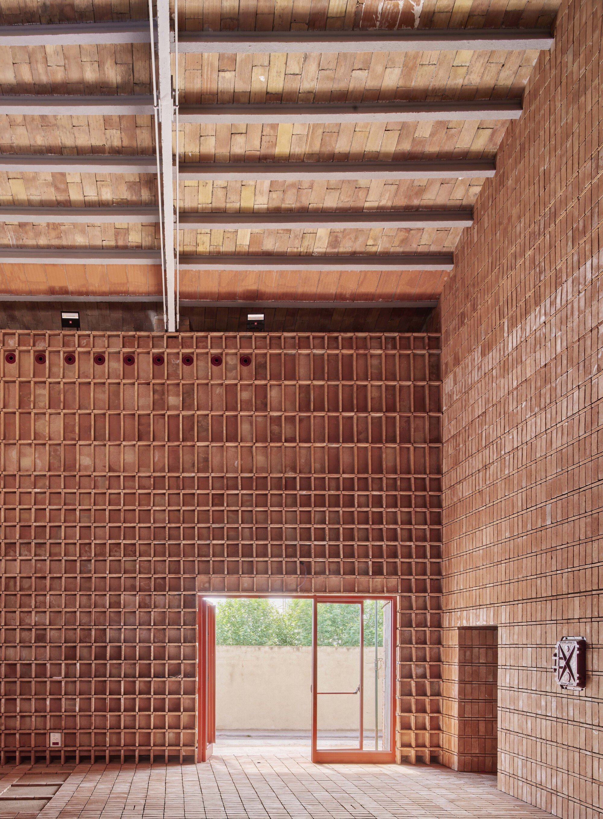 View toward the glass door with open-grid brick wall and timber beam ceiling in soft afternoon light