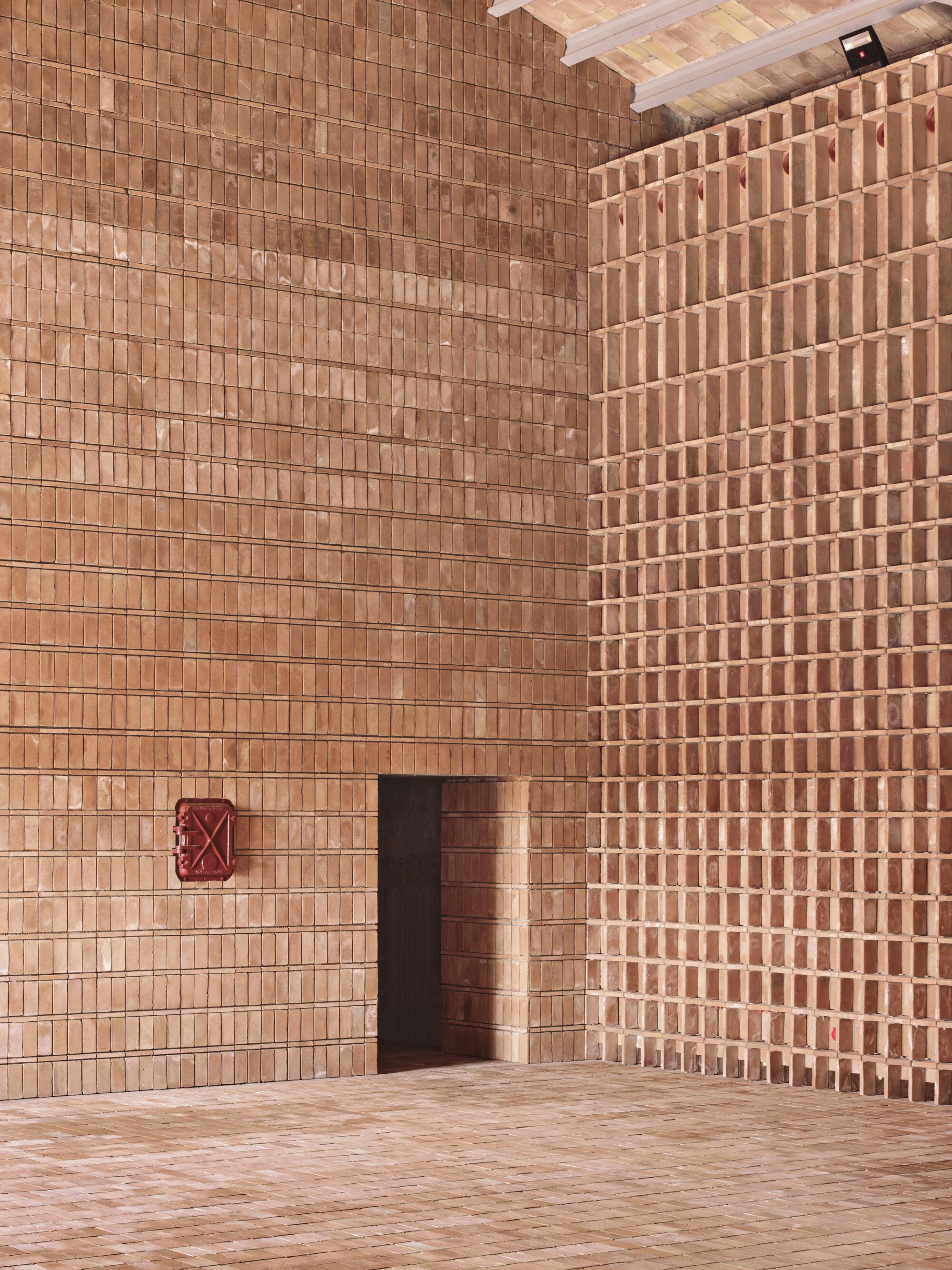 Corner view of doorway in terracotta brick wall with alternating open and solid coursing patterns