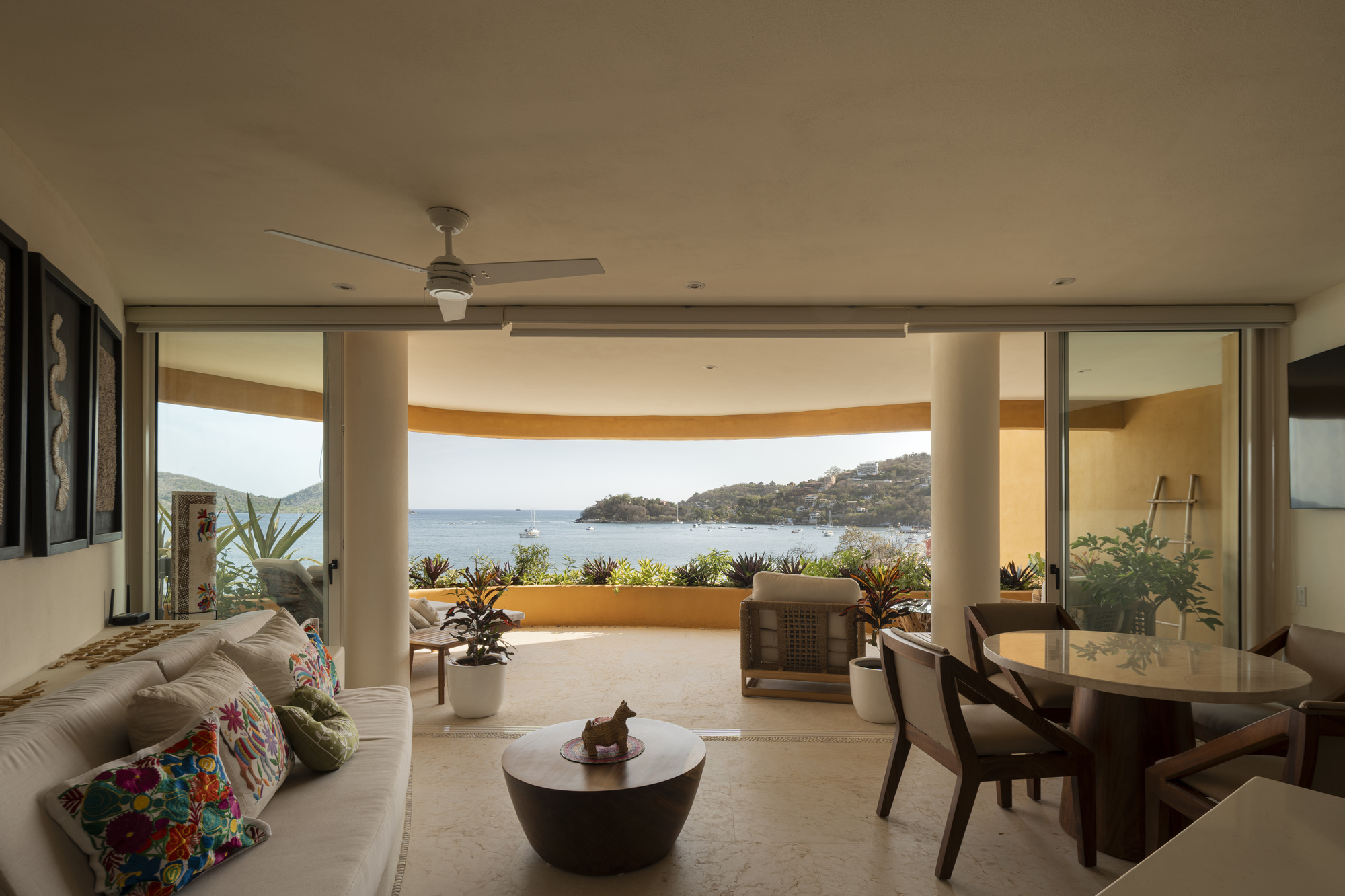 Living room opening onto a curved terrace with planted balustrade and sweeping views of the water