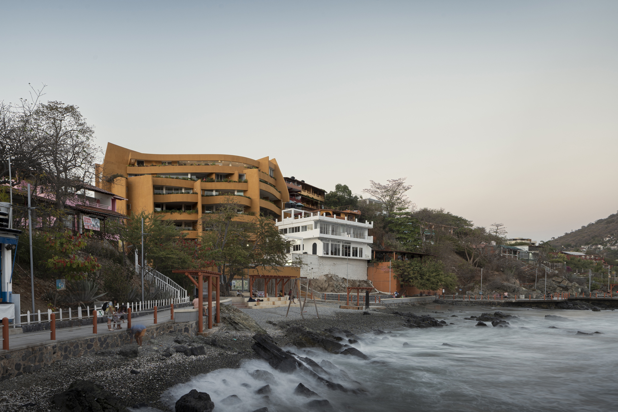 Oceanfront elevation showing stacked volumes above rocky shoreline with long exposure waves
