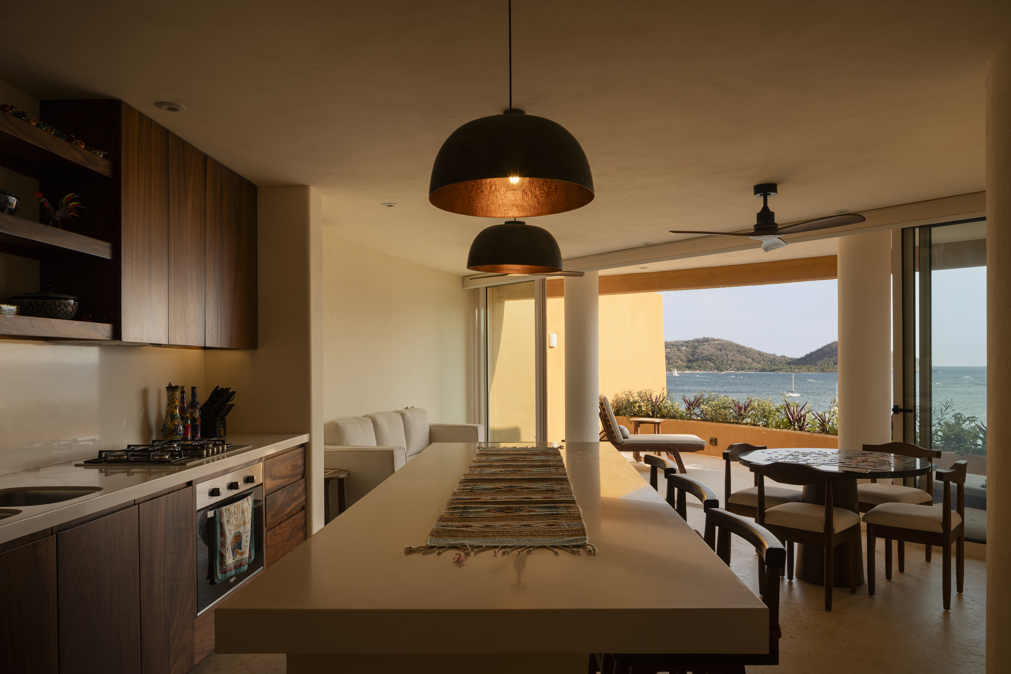 Open kitchen and dining area with pendant lights looking through to the ocean terrace