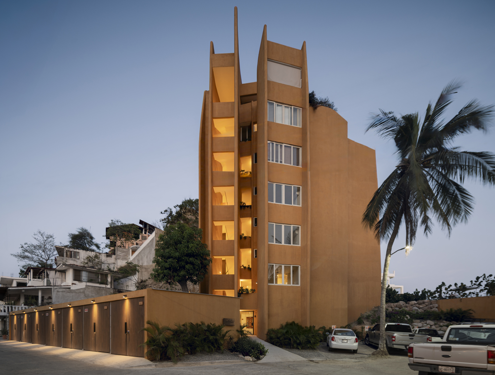 Street view of the ochre tower with vertical window openings lit from within at dusk