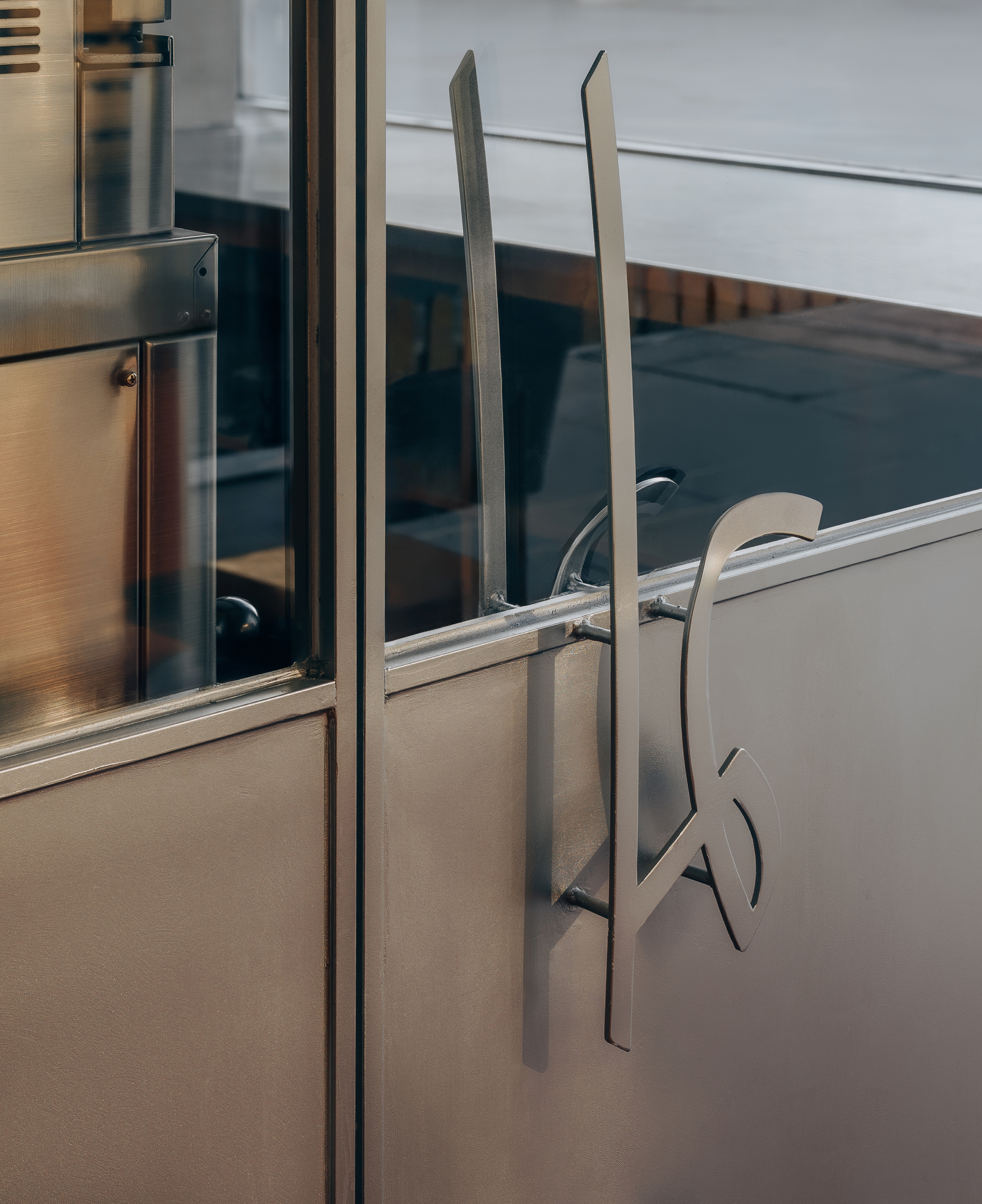 Custom door handle with fork-shaped stainless steel pull on brushed metal and glass surface
