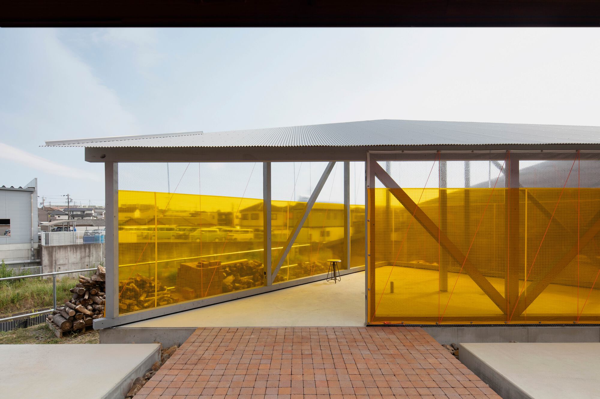 Covered exterior walkway with yellow perforated screen wall and diagonal timber bracing