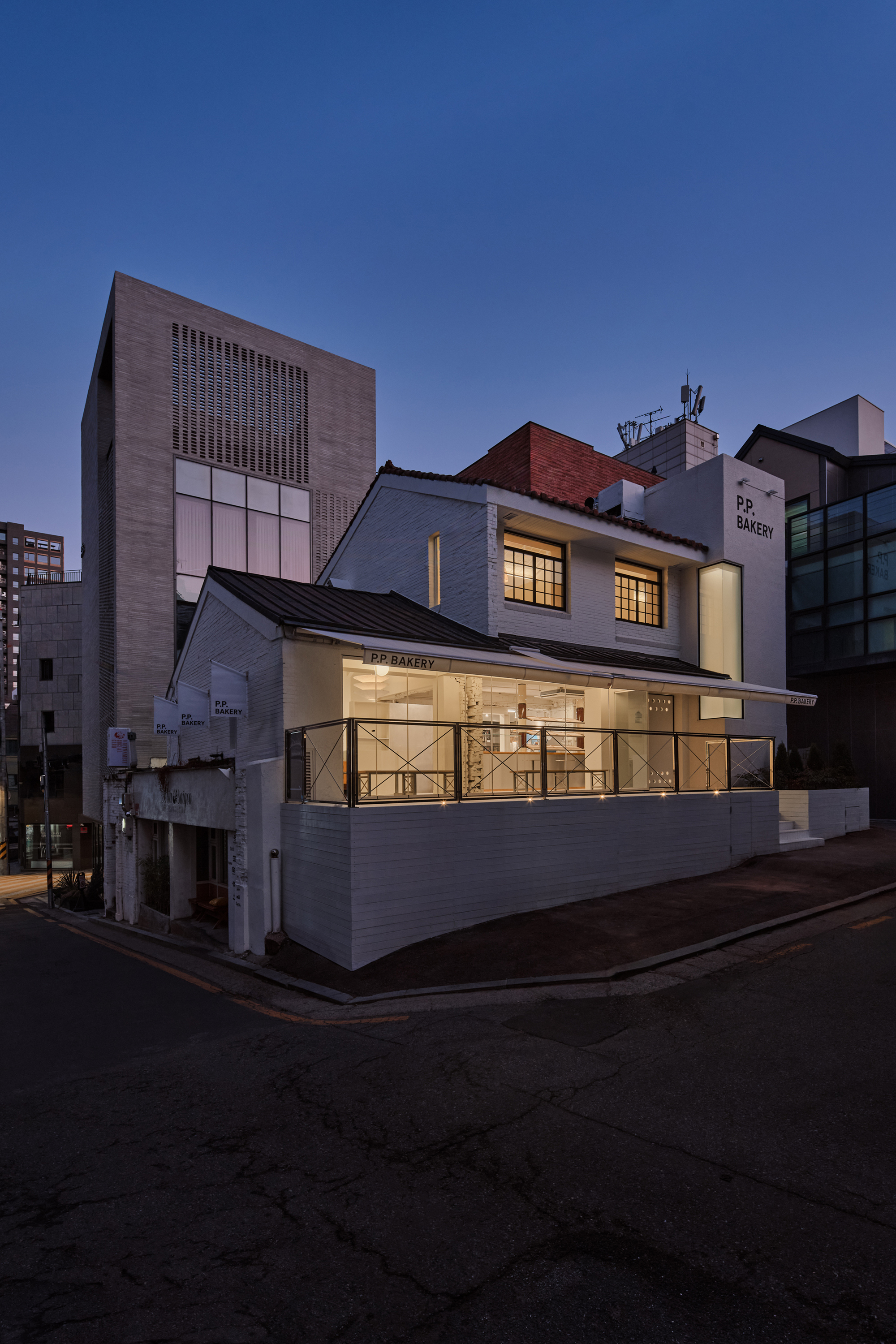 Wider street view of the bakery showing its position between taller neighbouring buildings