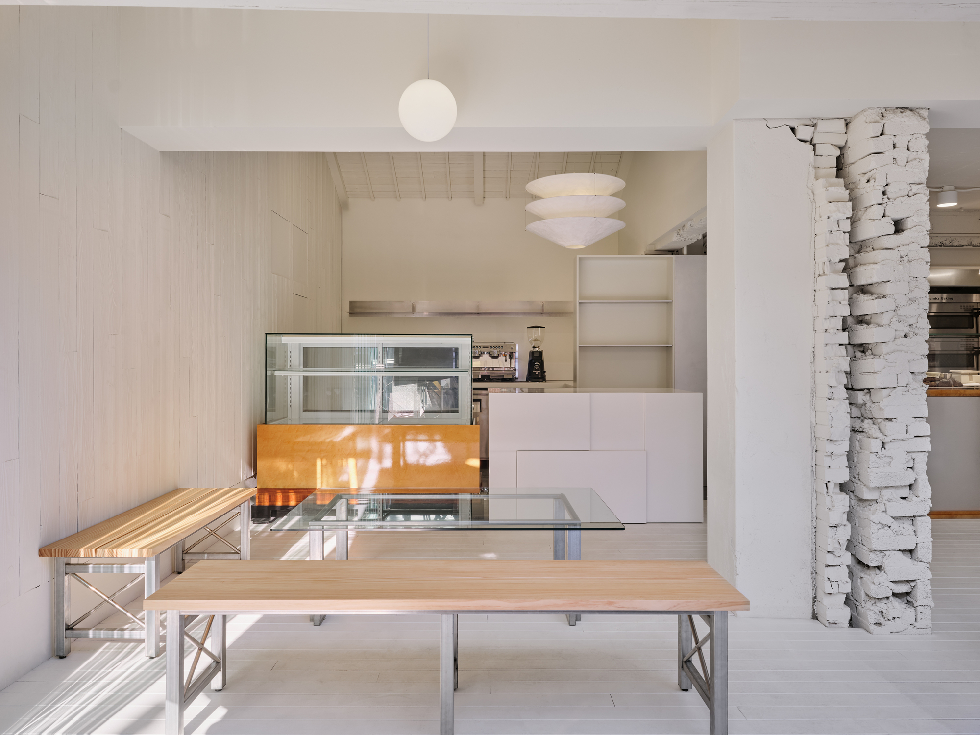 Ground-floor seating area with a long timber table beside an exposed plaster column