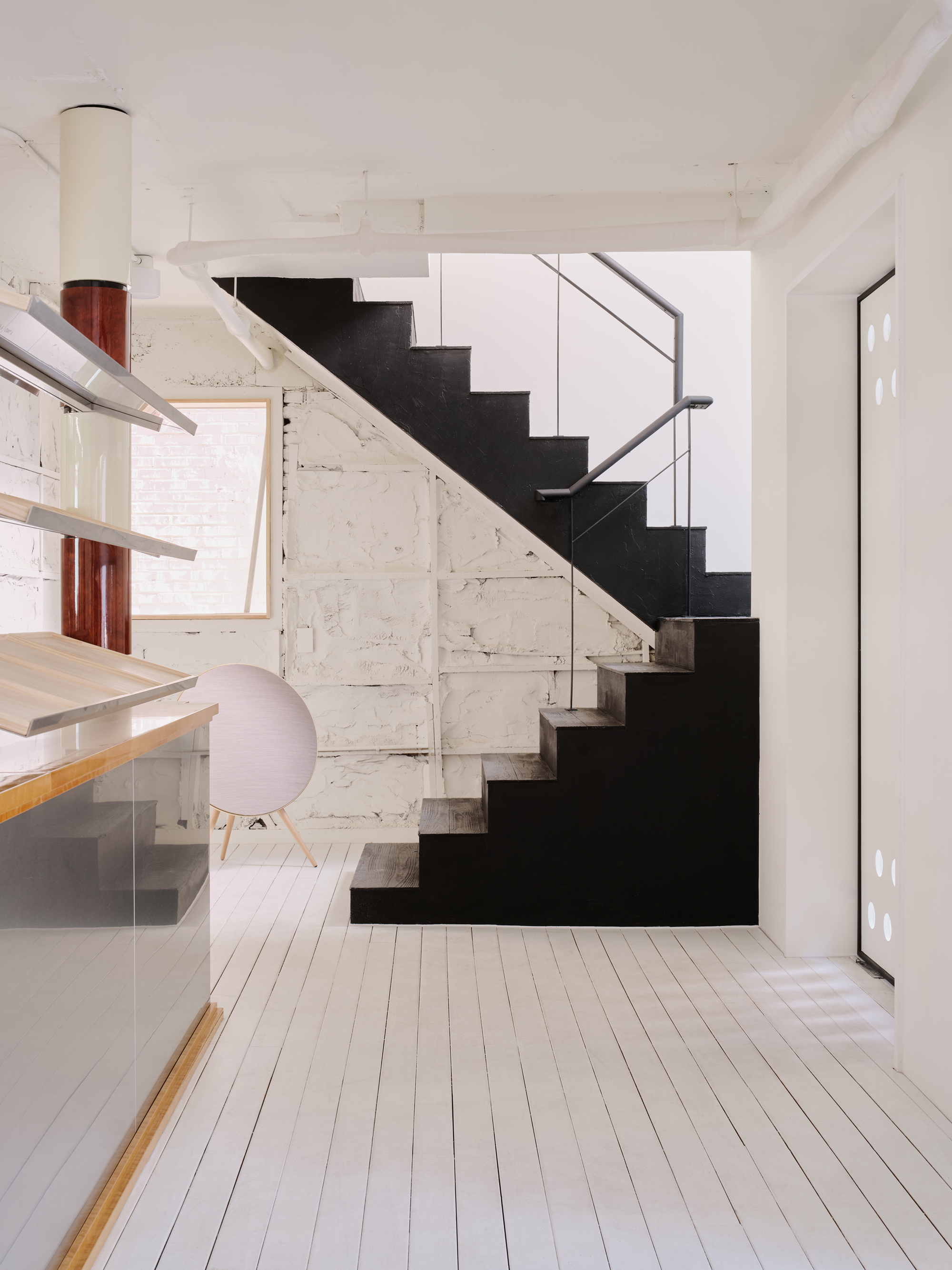 Ground floor with a black steel stair rising against the original raw plaster wall