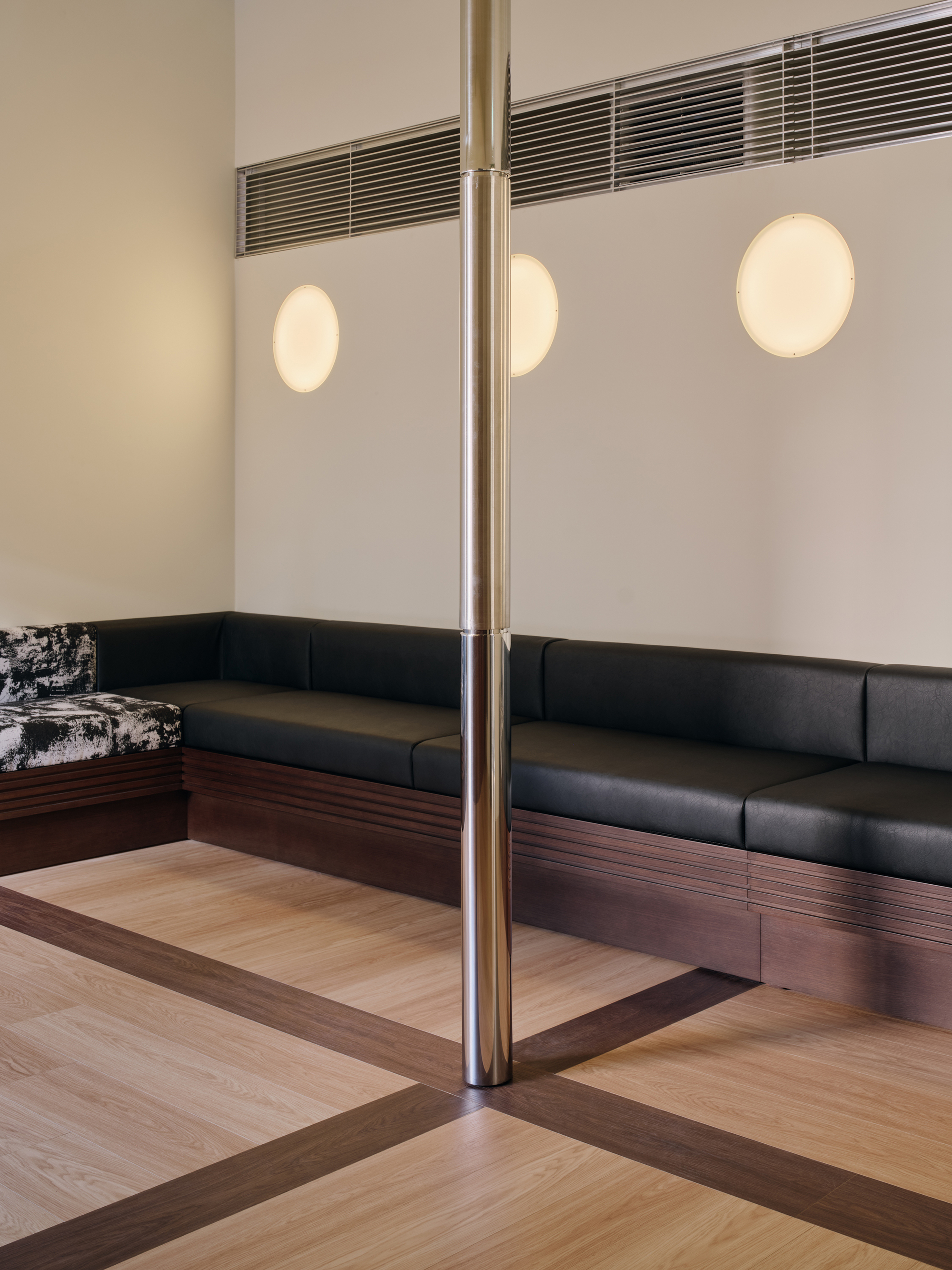 Banquette corner under three circular sconces with the steel column and timber floor border