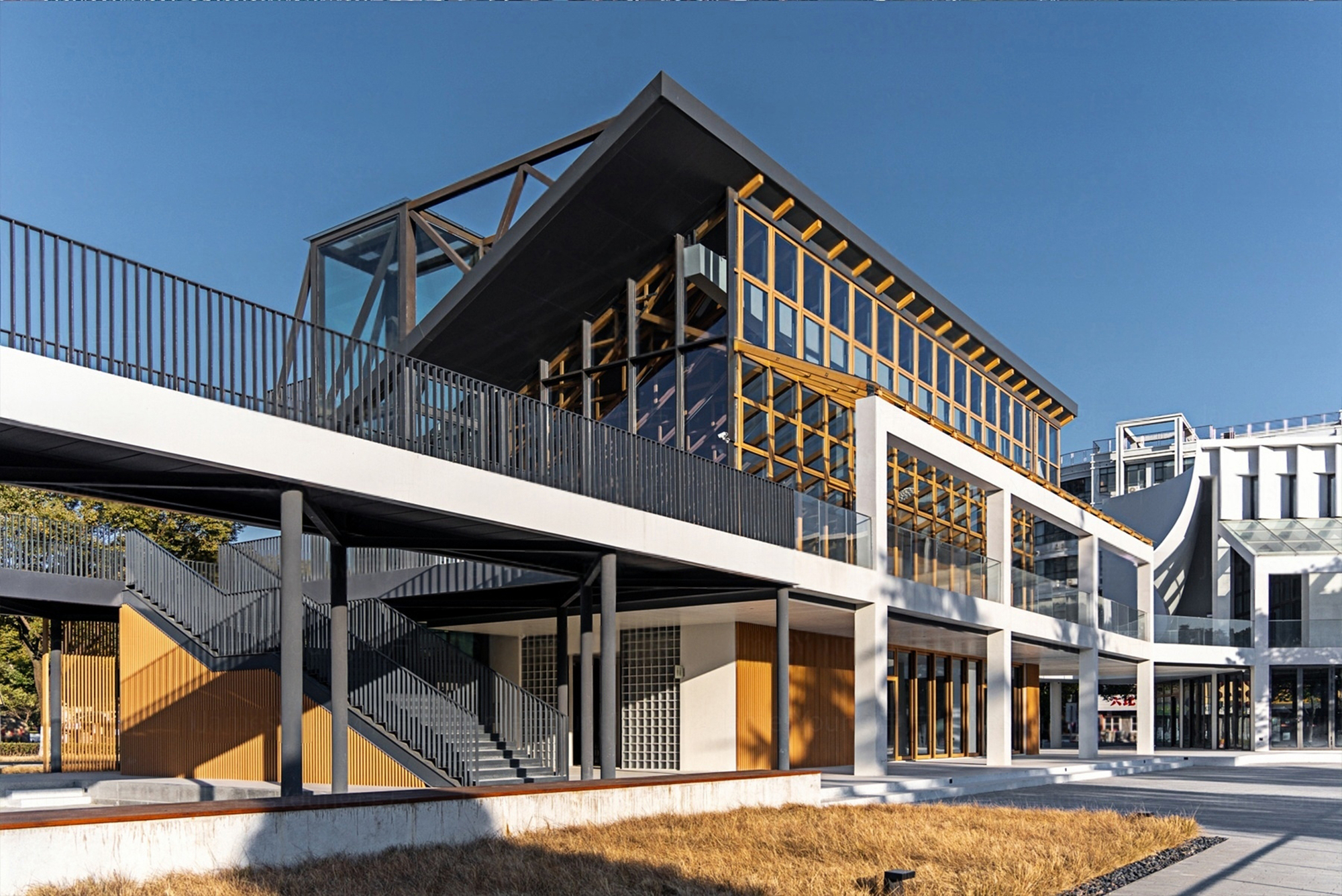 Facade showing the exposed timber frame with glass infill and corrugated metal cladding in afternoon light