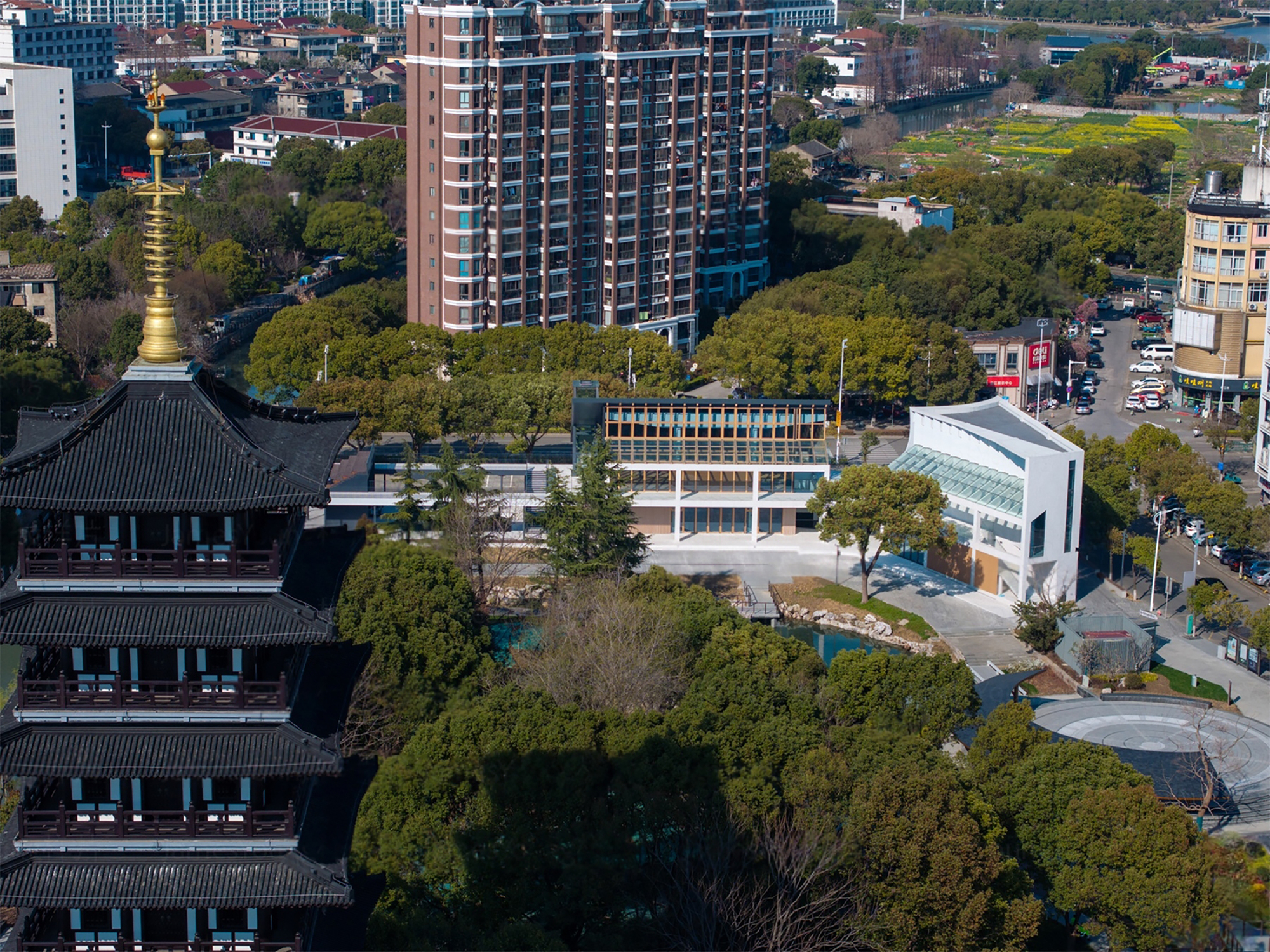 Aerial view showing the building complex surrounded by lush tree canopy and a traditional pagoda tower