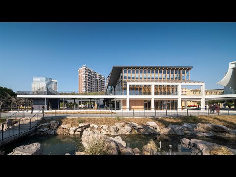 Front elevation showing the glazed facade and elevated roof canopy above a water feature with rocks