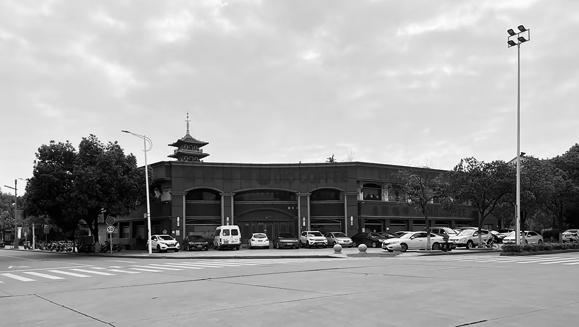 Street view of the arched facade with parked cars and a pagoda tower visible in the background