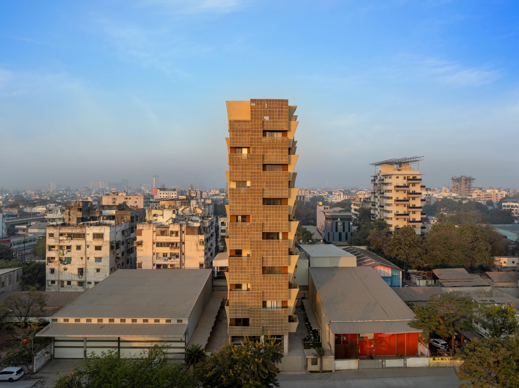 Stacked brick tower rising above a dense urban neighborhood at dusk