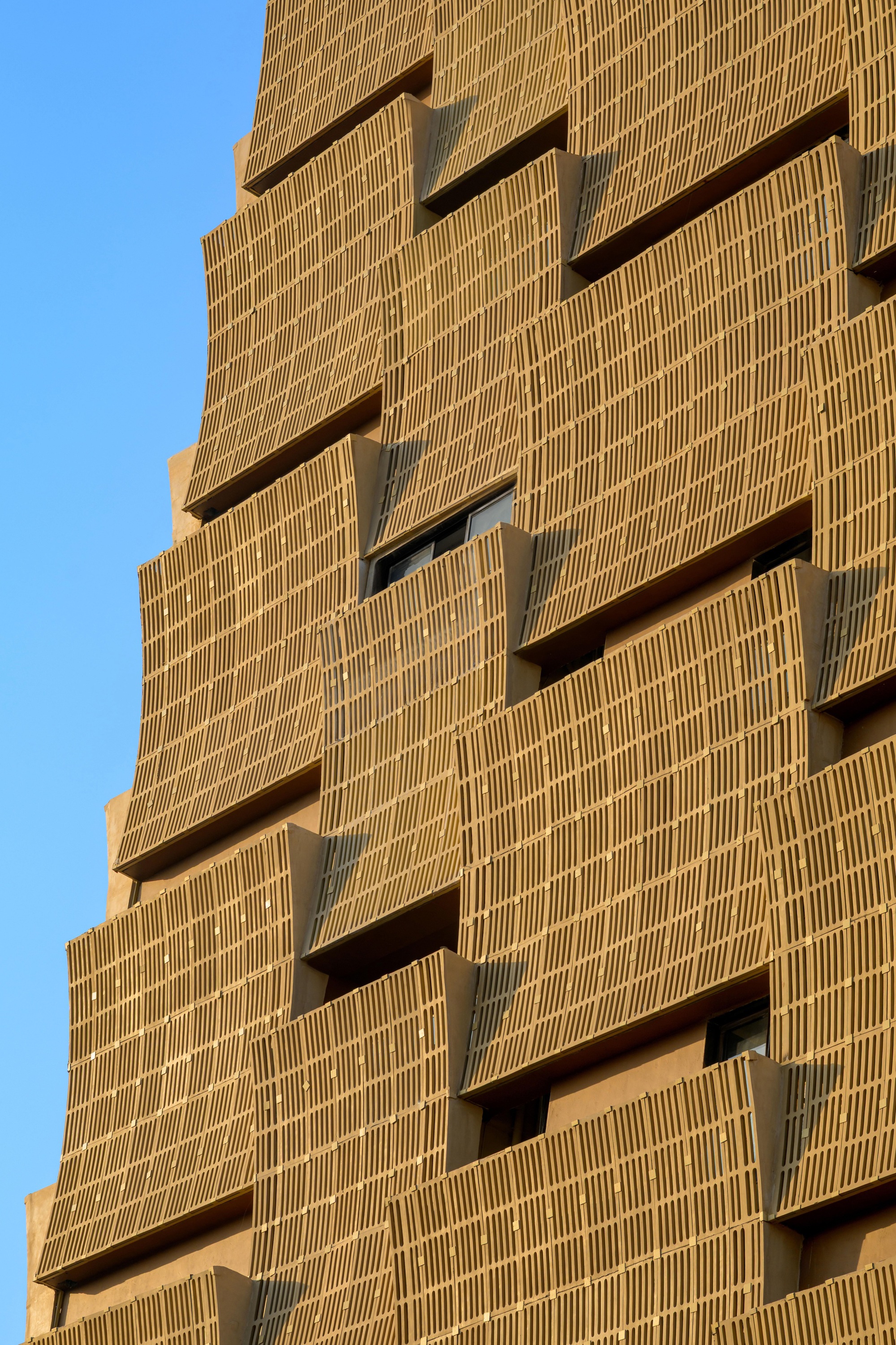 Close-up of the staggered brick facade showing recessed balconies and deep shadows