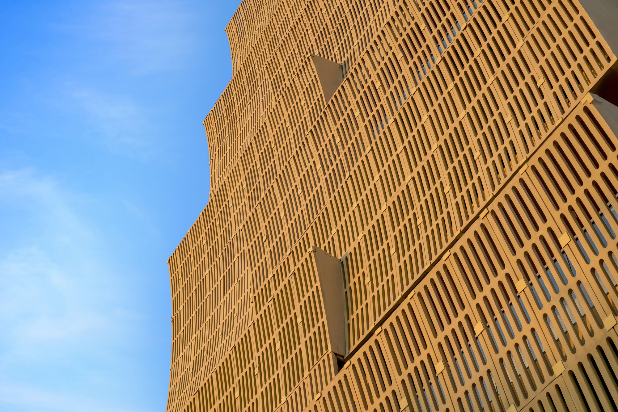 Facade detail showing vertical slats and triangular recesses in warm afternoon light
