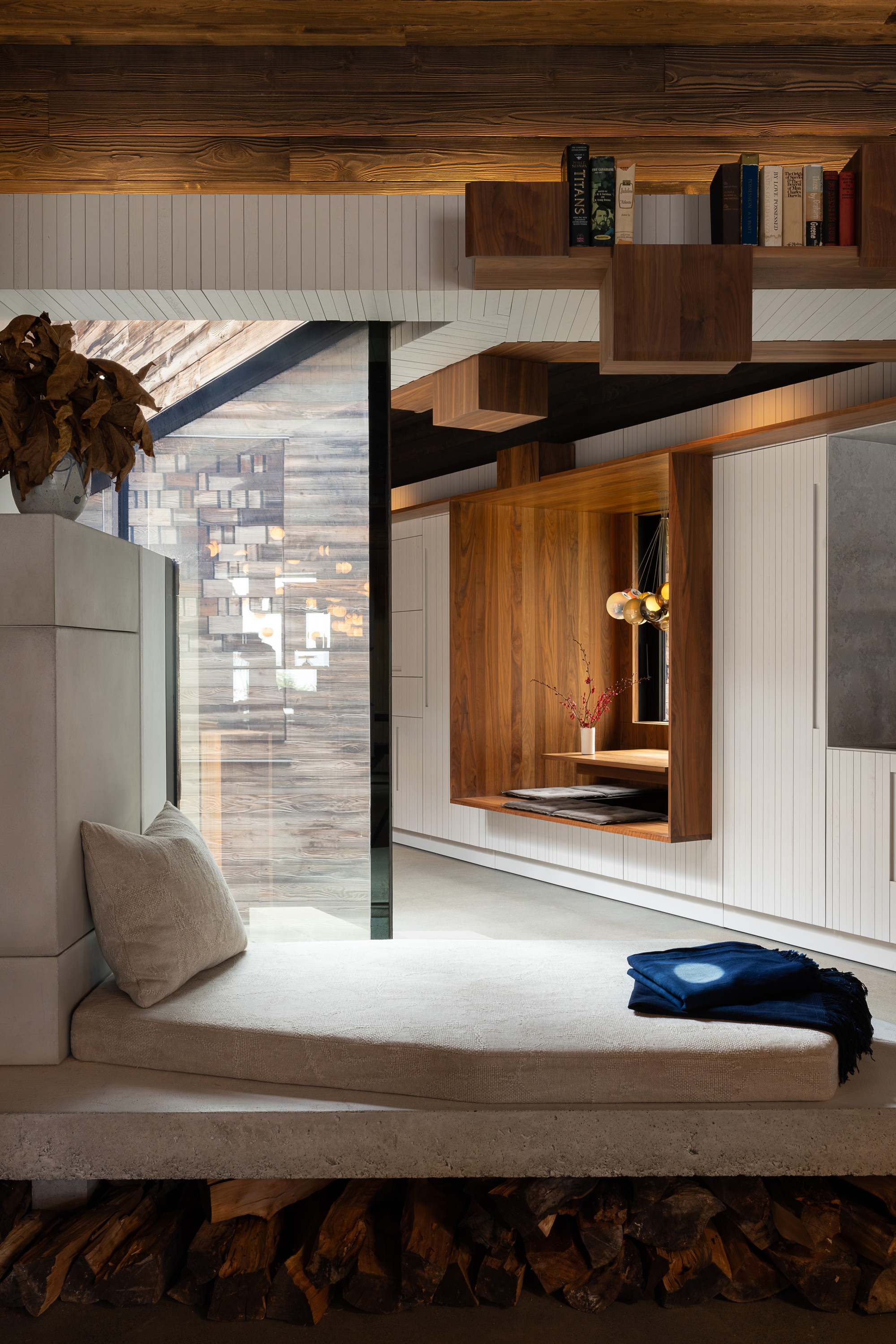 Interior view showing integrated wall storage with vertical white cladding and walnut box shelves in daylight