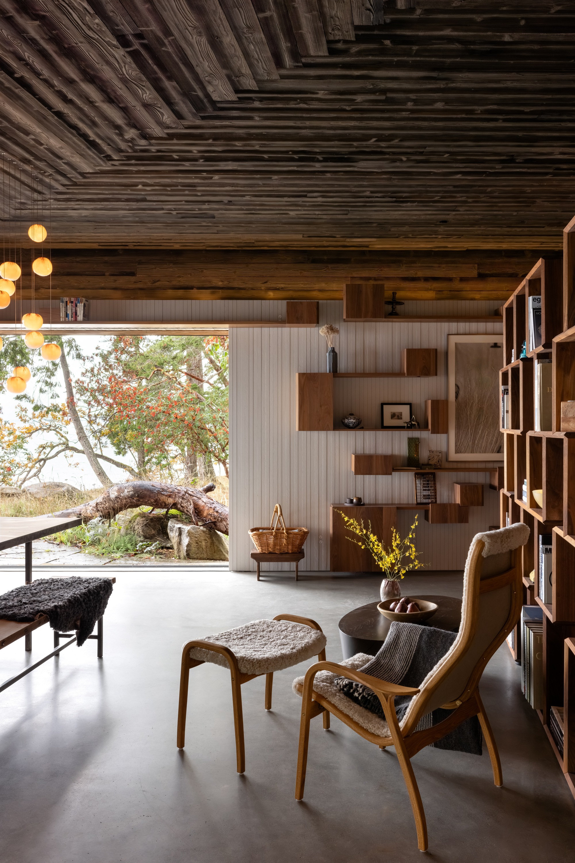 Living room with exposed timber ceiling and large window framing autumn trees outside