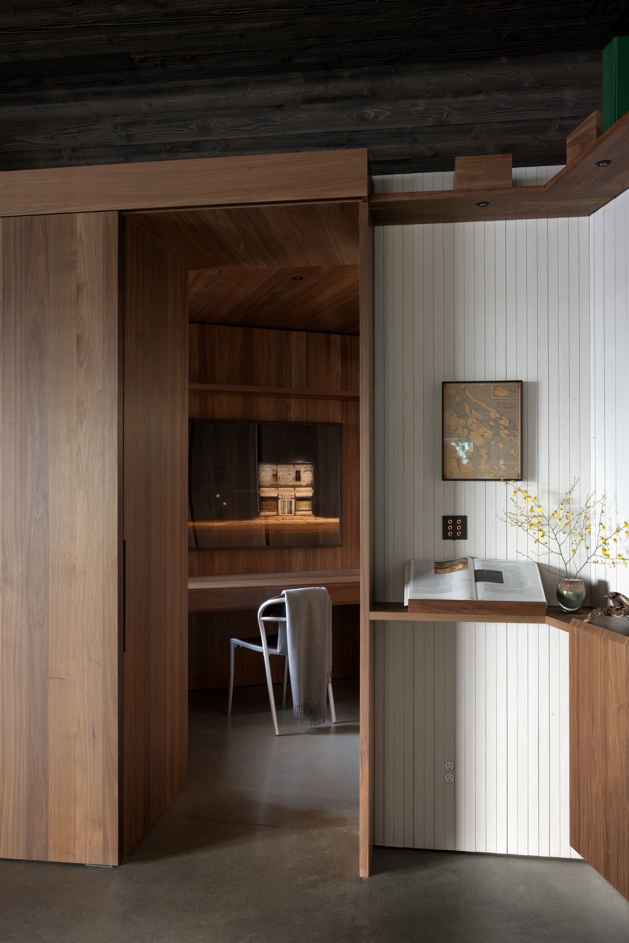 Timber-framed doorway opening into office niche with built-in desk and shelving