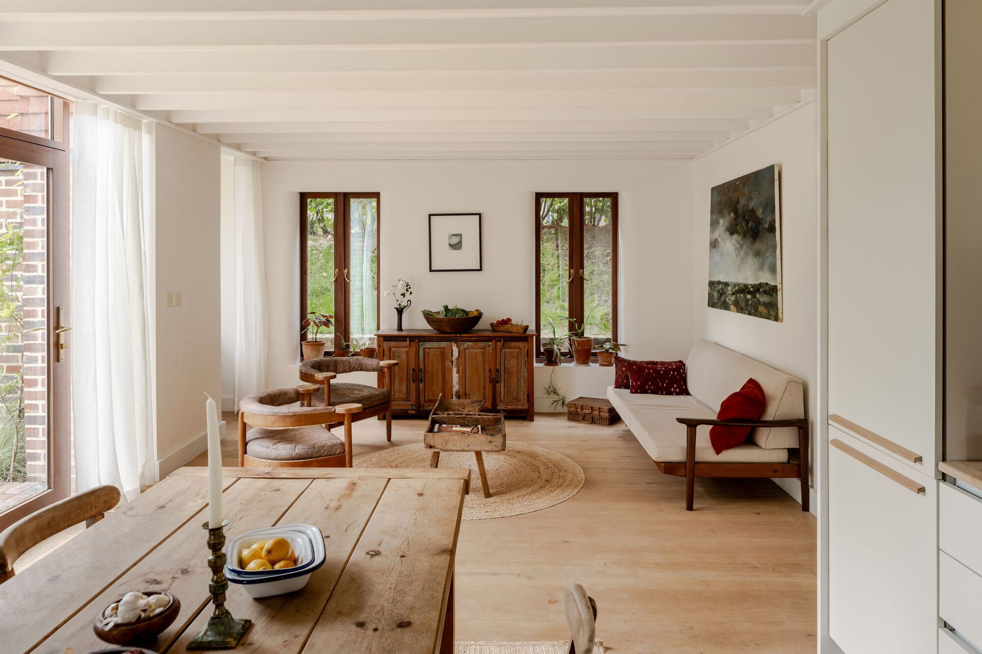 Open-plan living and dining area with pale timber flooring and paired vertical windows