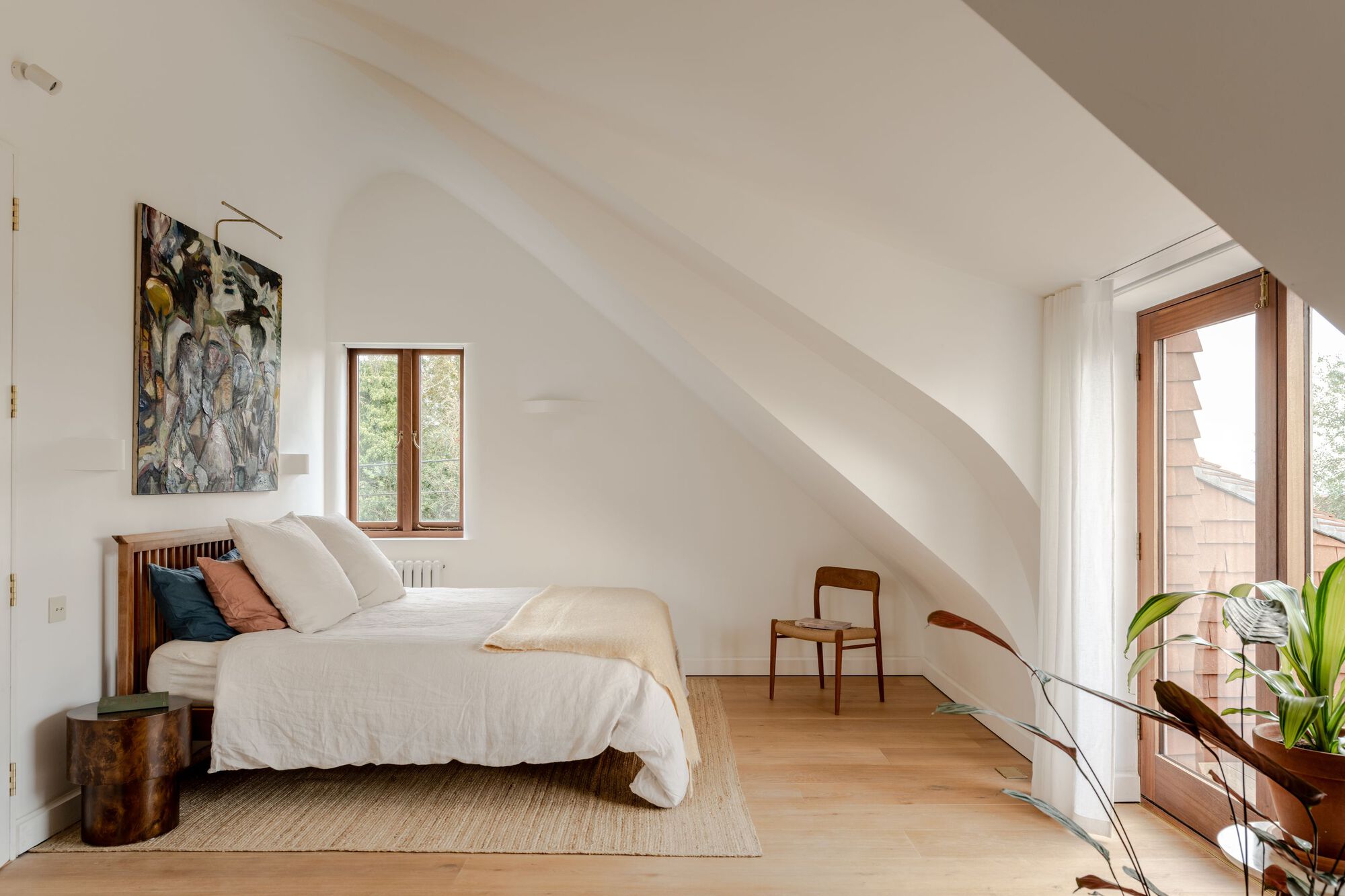 Bedroom with vaulted ceiling and timber-framed doorway opening to exterior deck