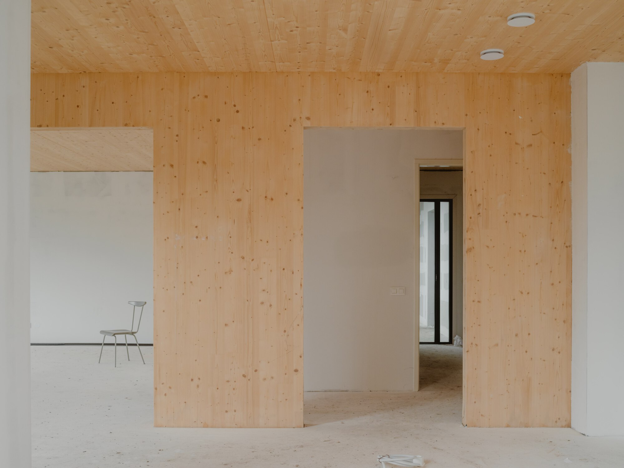 Interior doorway framed by light plywood walls and ceiling with view through to adjacent room