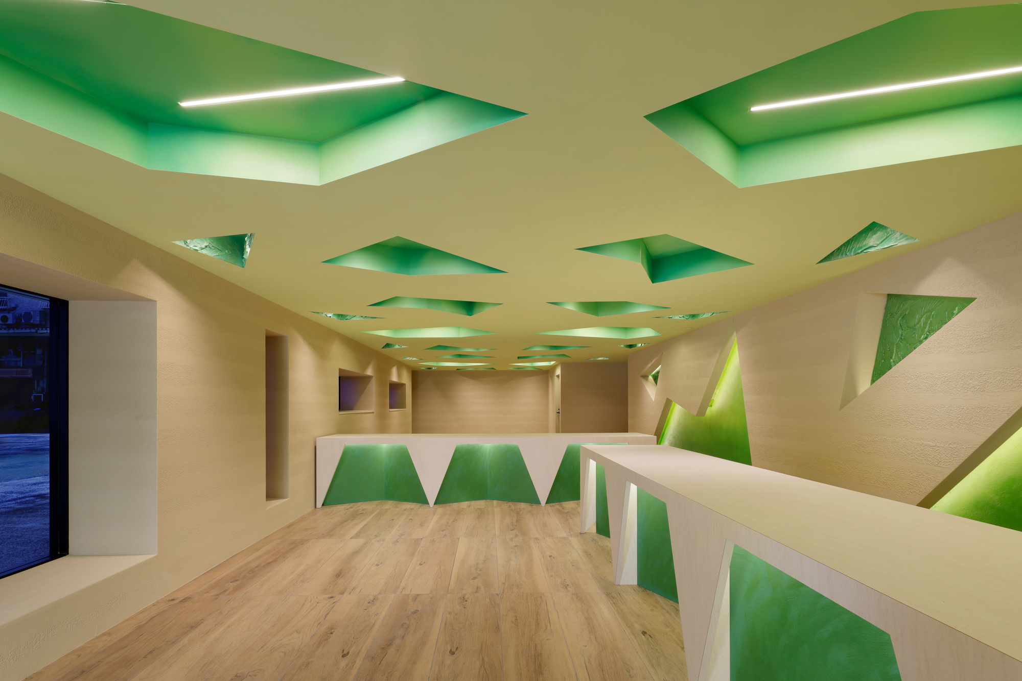 Wide office view with the patterned ceiling, faceted counters and a window at the far end