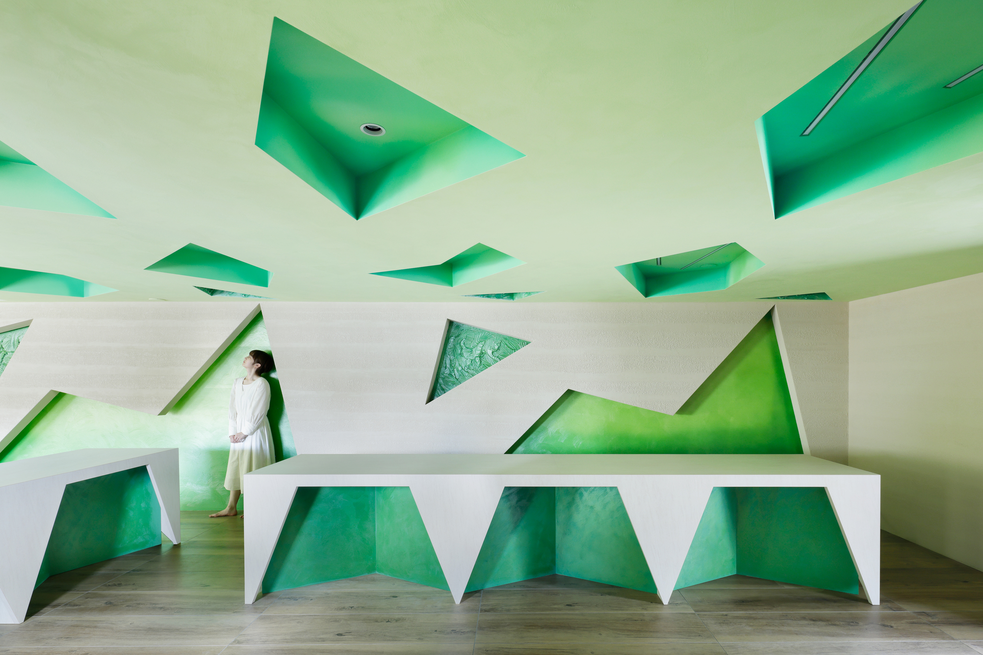 Reception desk and rear wall covered in triangular green panels of varying sizes