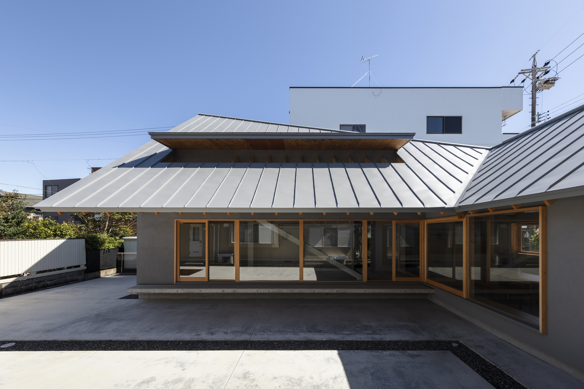Courtyard view of the standing seam metal roof canopy with timber framing over full-height glazed doors