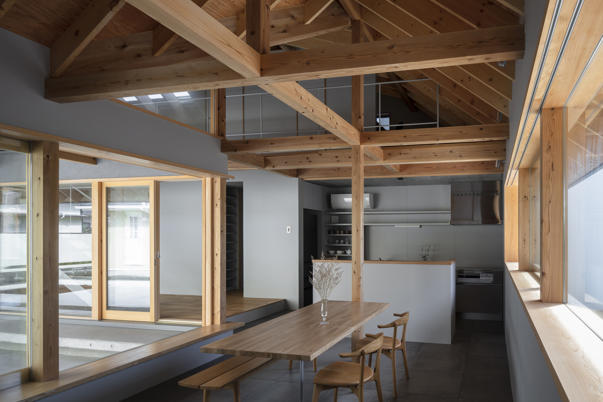 Dining area with exposed timber post-and-beam structure and skylights illuminating the wood ceiling