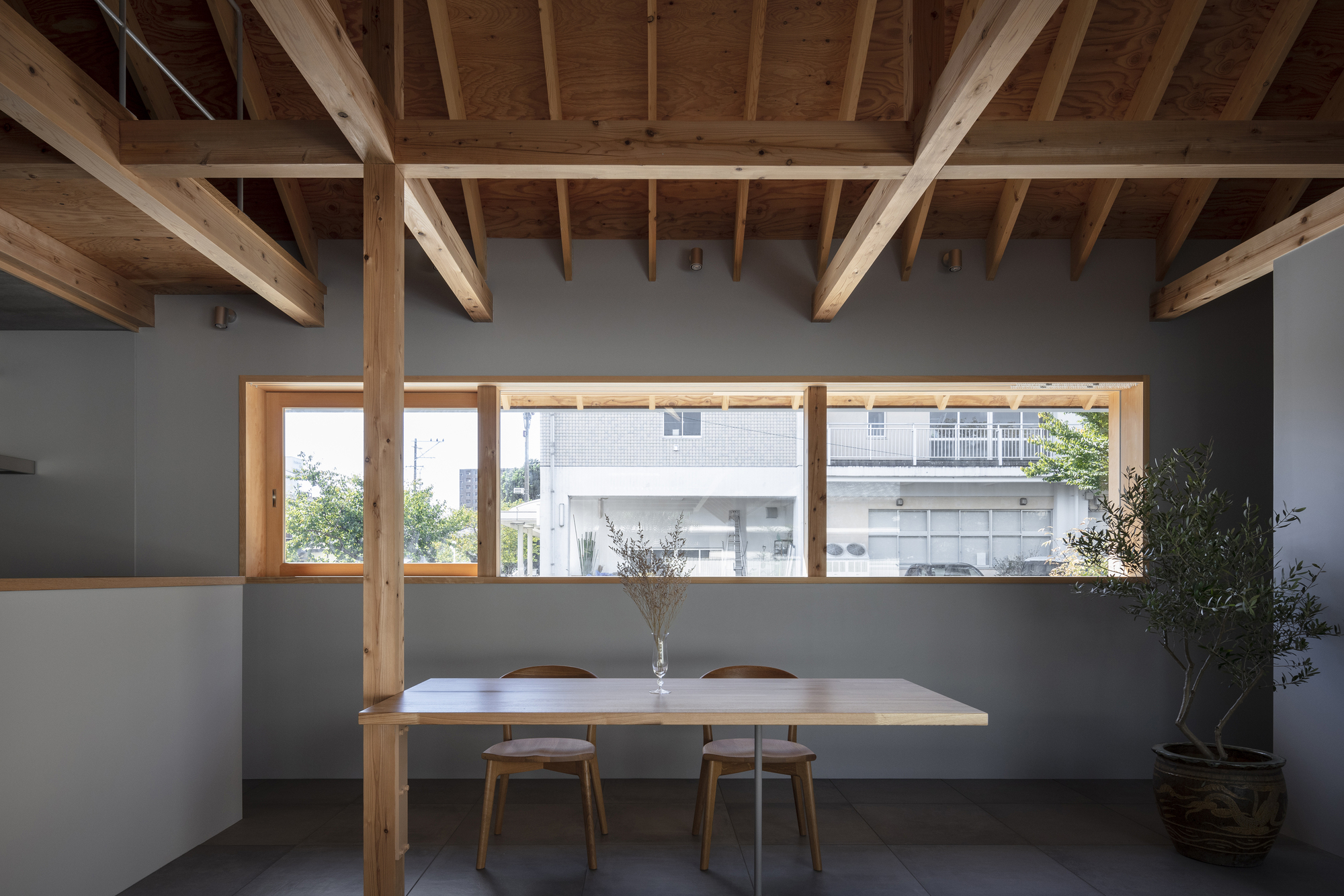 Interior dining space with horizontal window framing a view of the neighboring buildings beyond